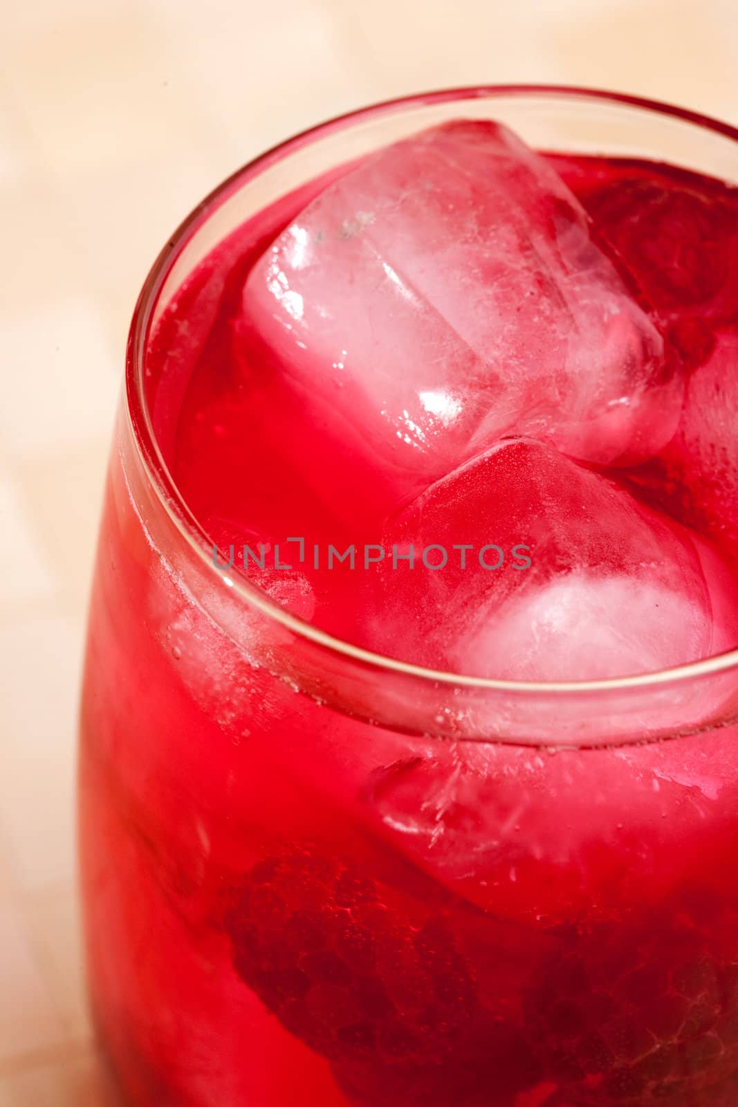 A glass of sparkling raspberry punch outdoors in a natural setting