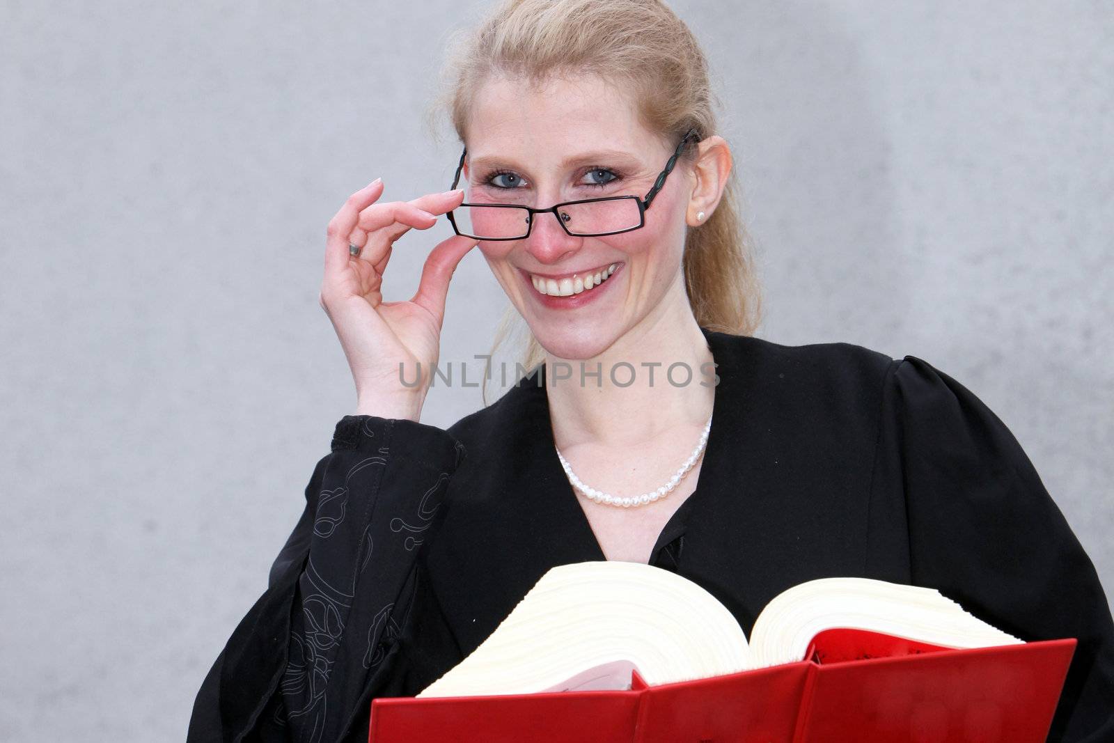 Law student holds a red book, laughing and looking towards the camera
