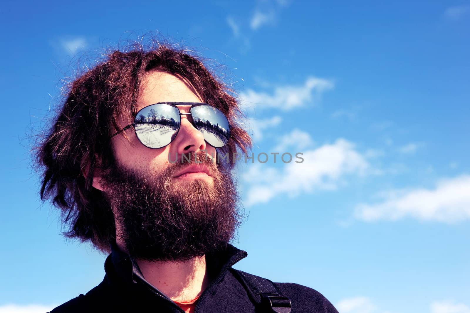 A male with a full beard and retro sunglasses standing in a winter landscape - cross processed