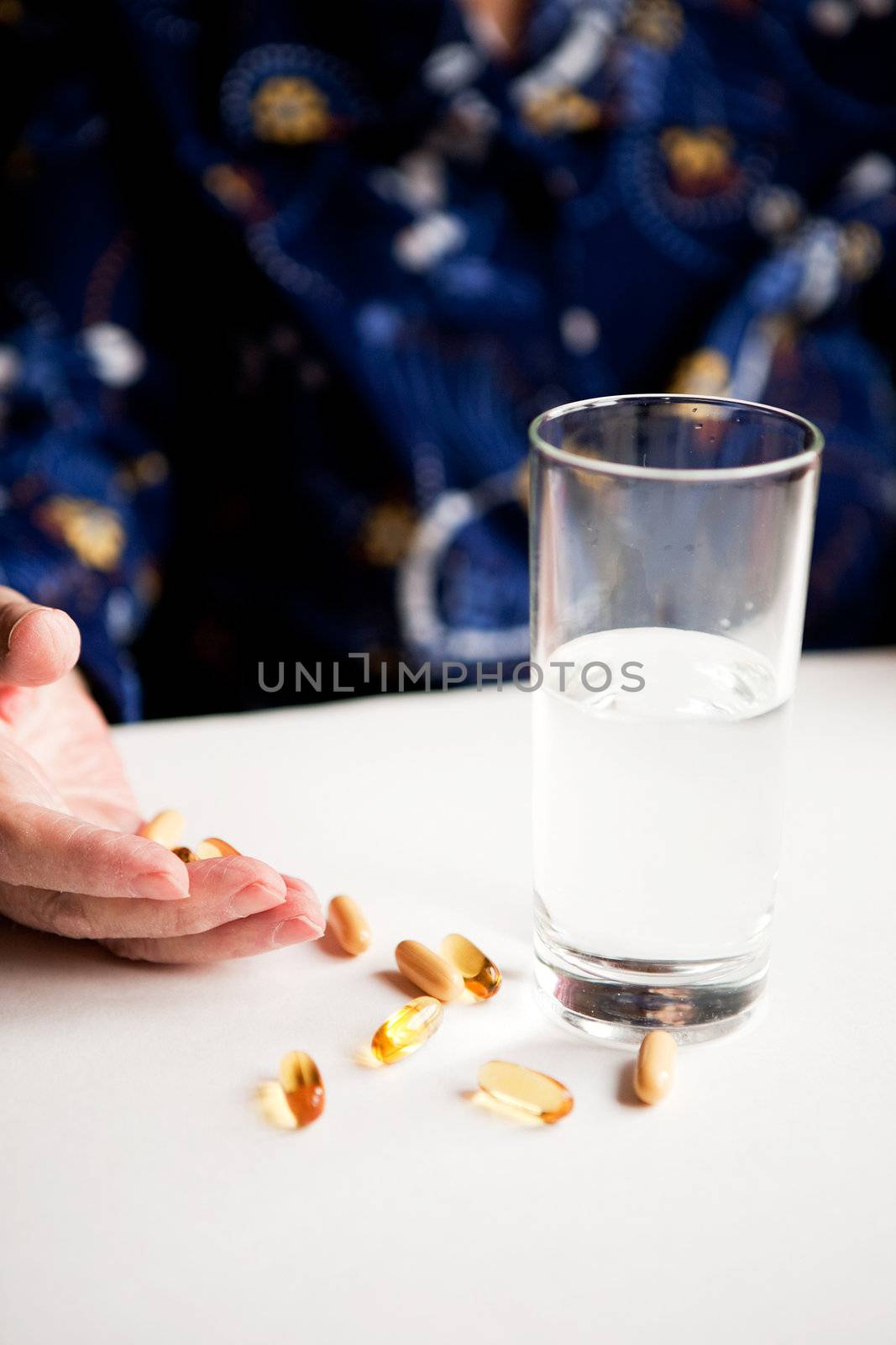 An elderly hand with a variety of large pills - shallow depth of field, focus on hand and pills