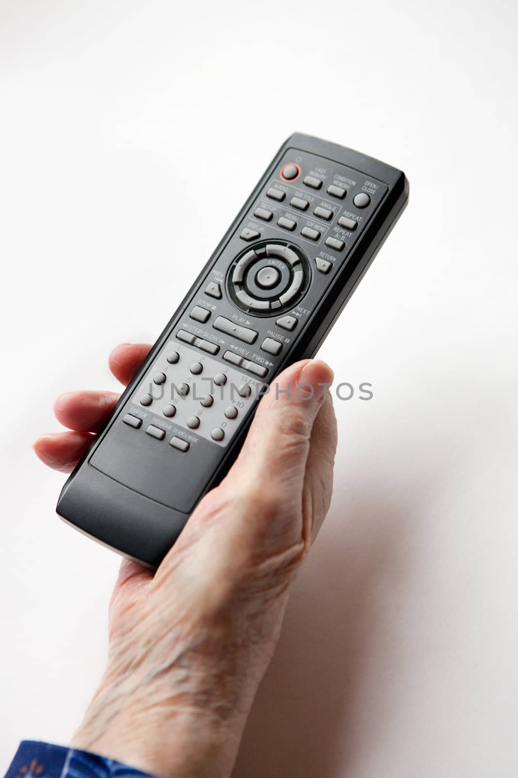 An elderly hand with a TV DVD remote control