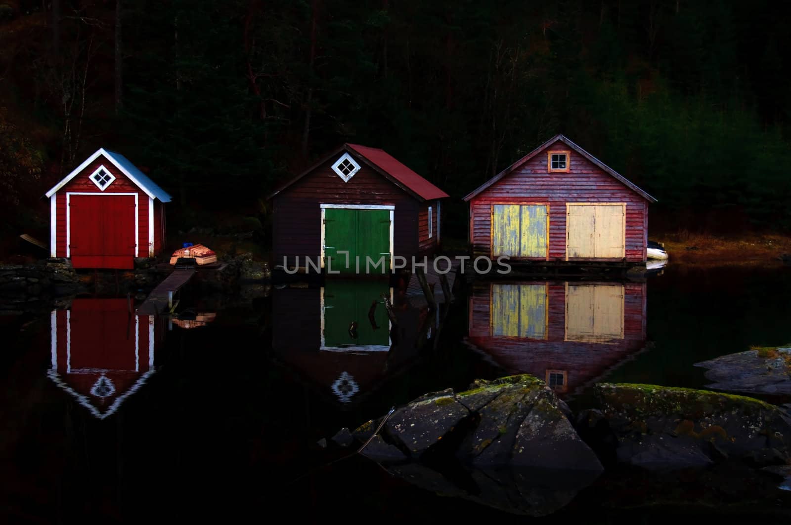 Three boathouses in the evening making reflections