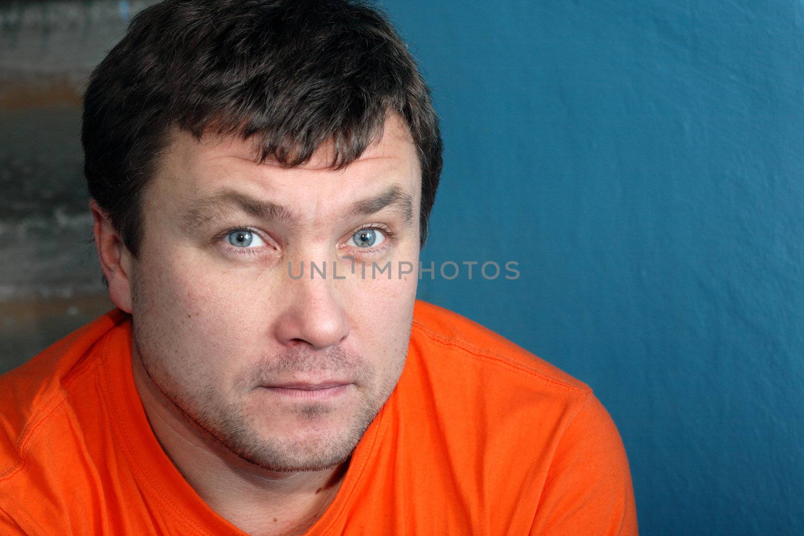 Serious young man portrait on background with old blue wall