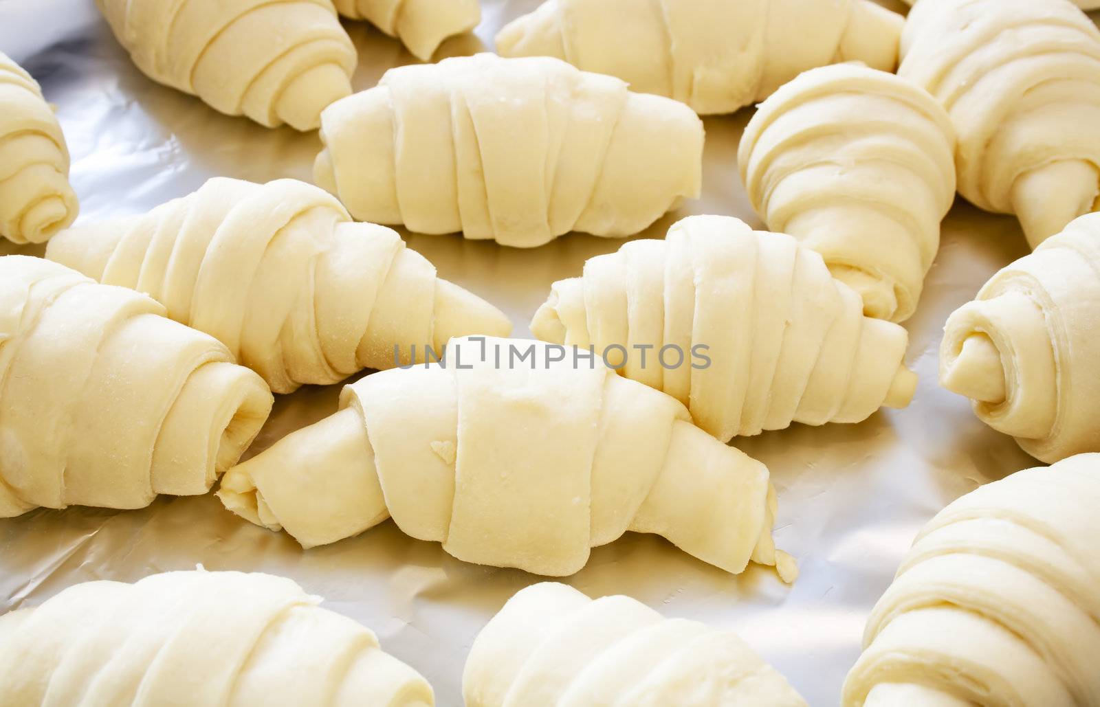 Croissants on aluminum foil prepared for baking