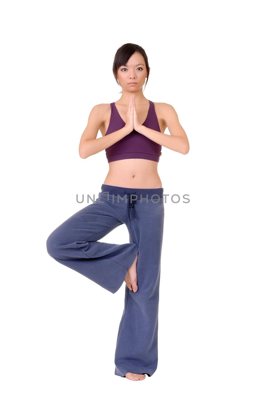 Young woman doing yoga excise by standing on one foot isolated over white.