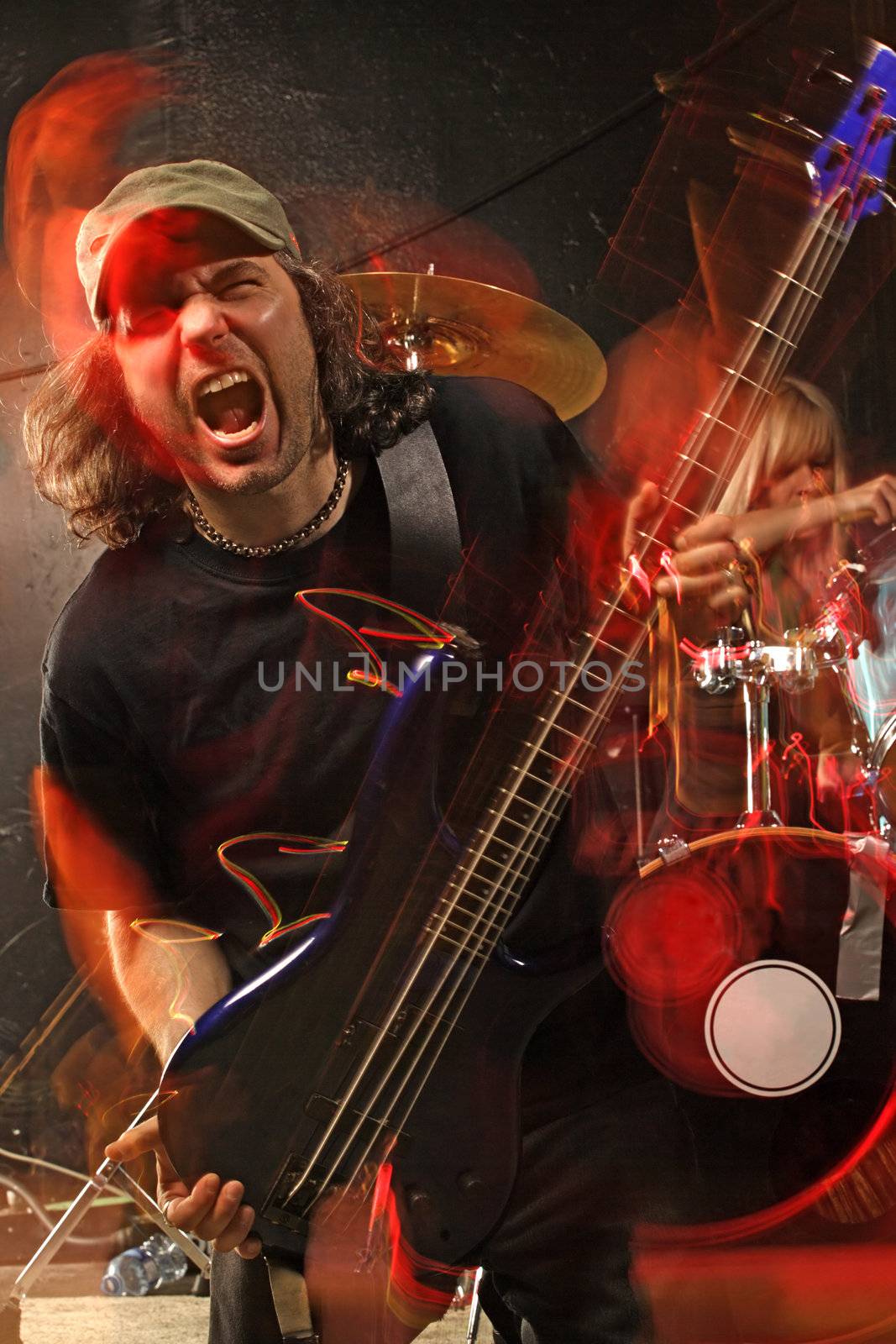 Bass guitarist playing on a stage. Shot with strobes and slow shutter speed to create lighting atmosphere and blur effects. Intense motion blur on performers.
