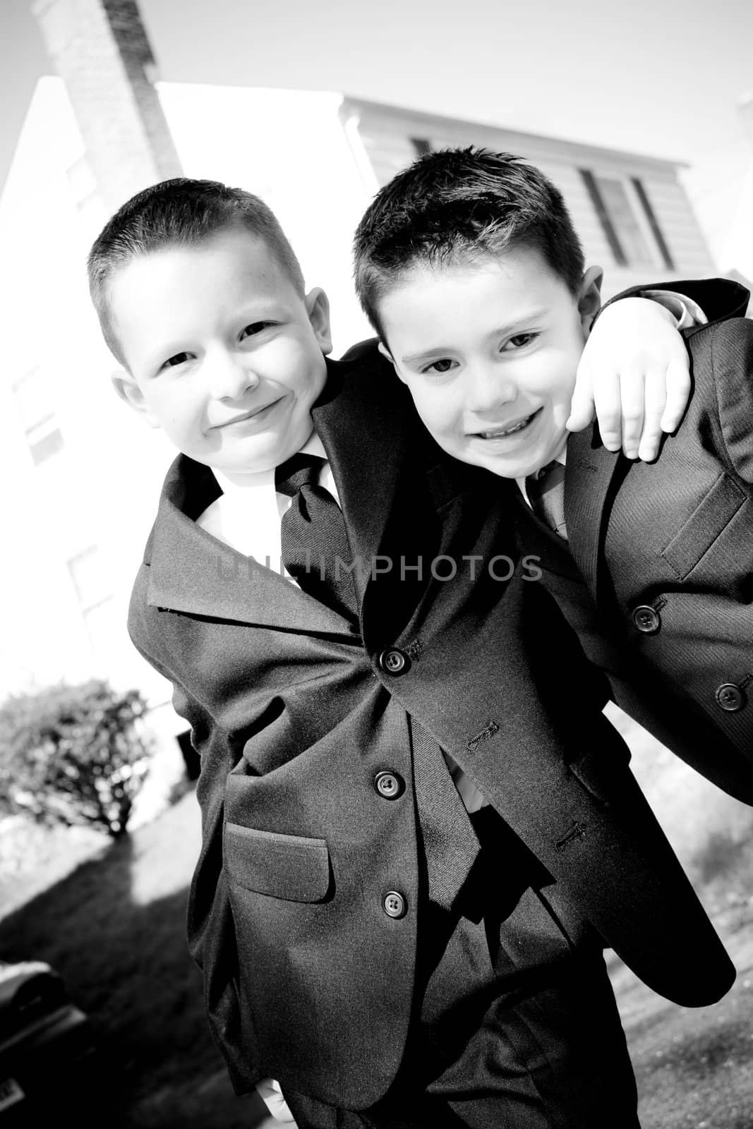 Two happy young boys dressed in suits with smiles on their faces.  Black and white.