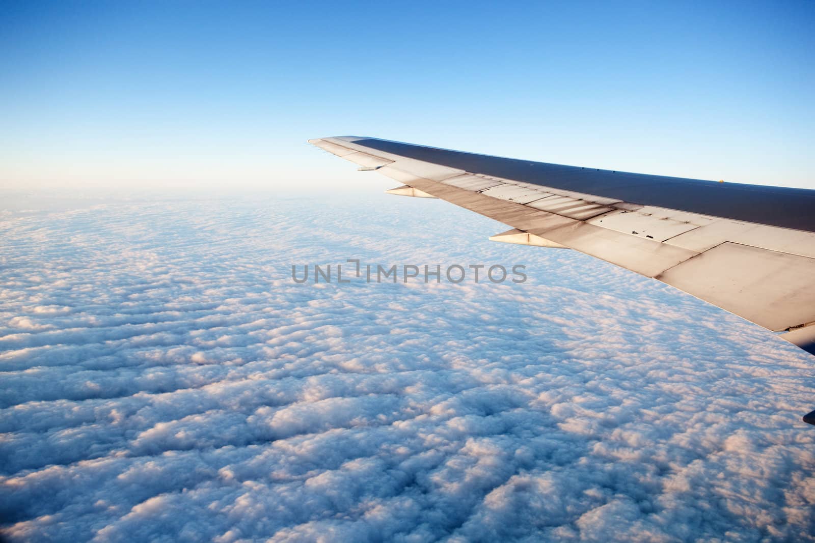 A wing of an airplane flying of a cloudscape