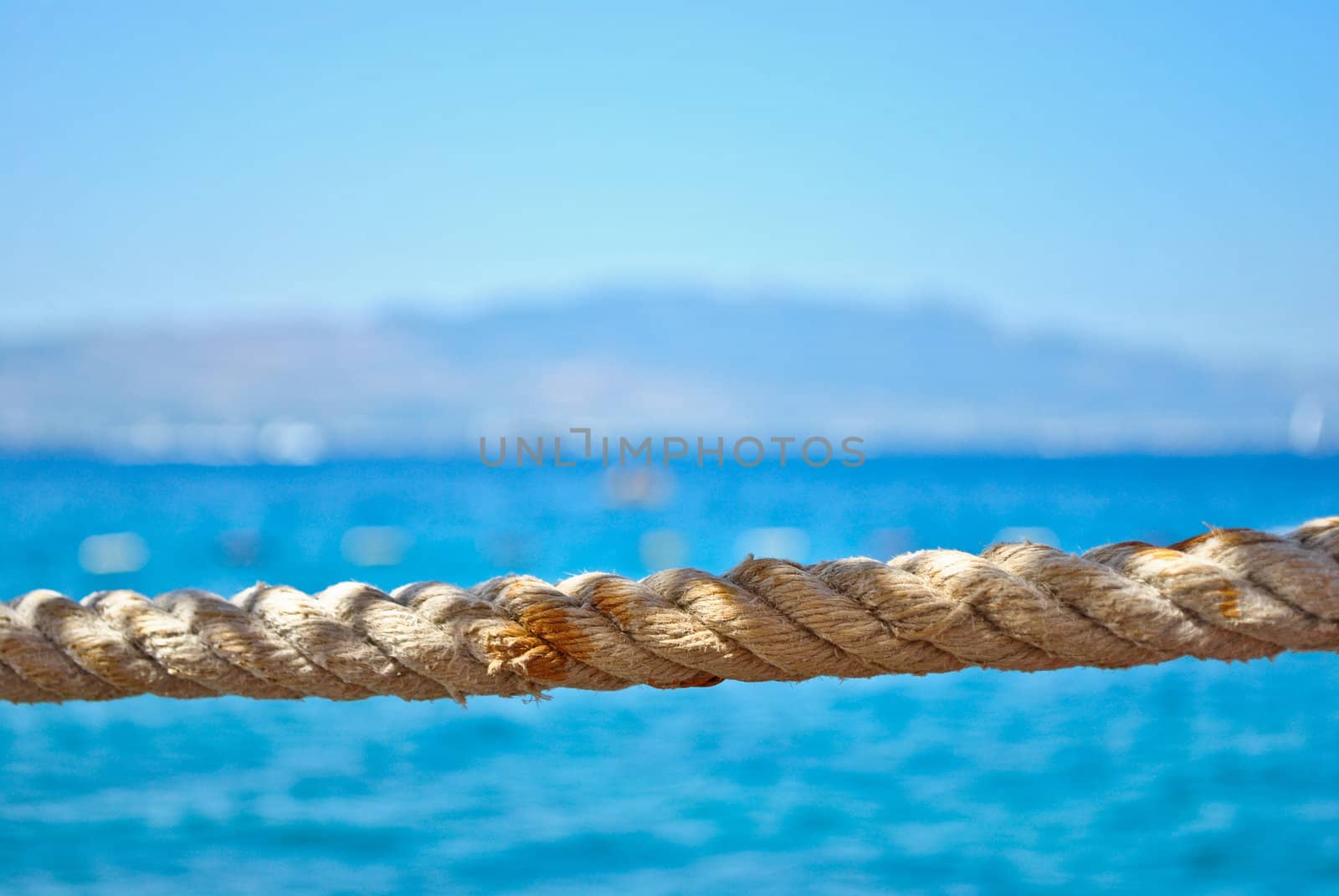 Old rope streched in front of blue, calm seawater in the summer