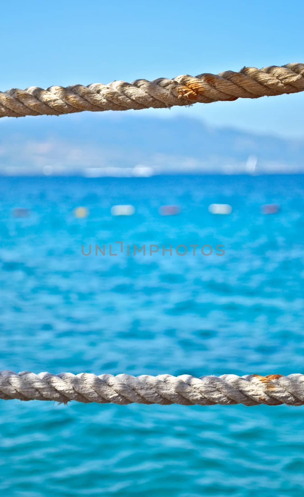 Two dld ropes streched in front of blue, calm seawater in the summer