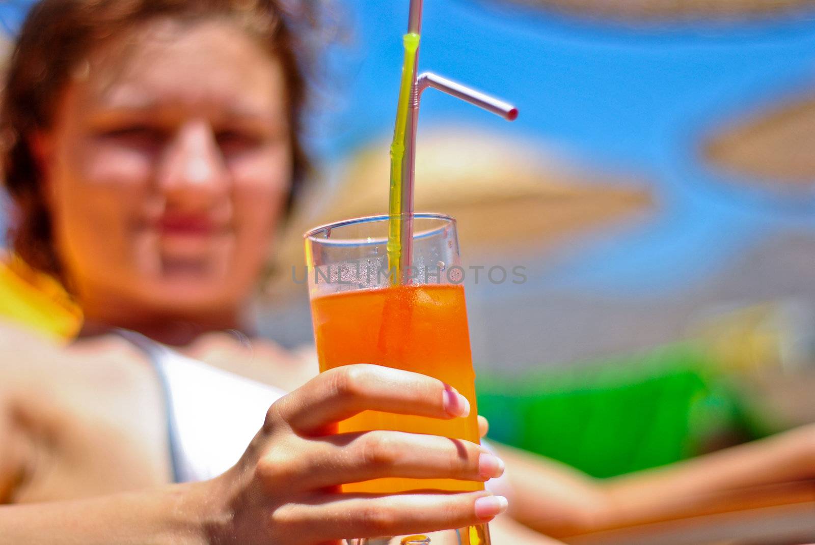 Young woman relaxing and drinking an orange cocktail with two straws