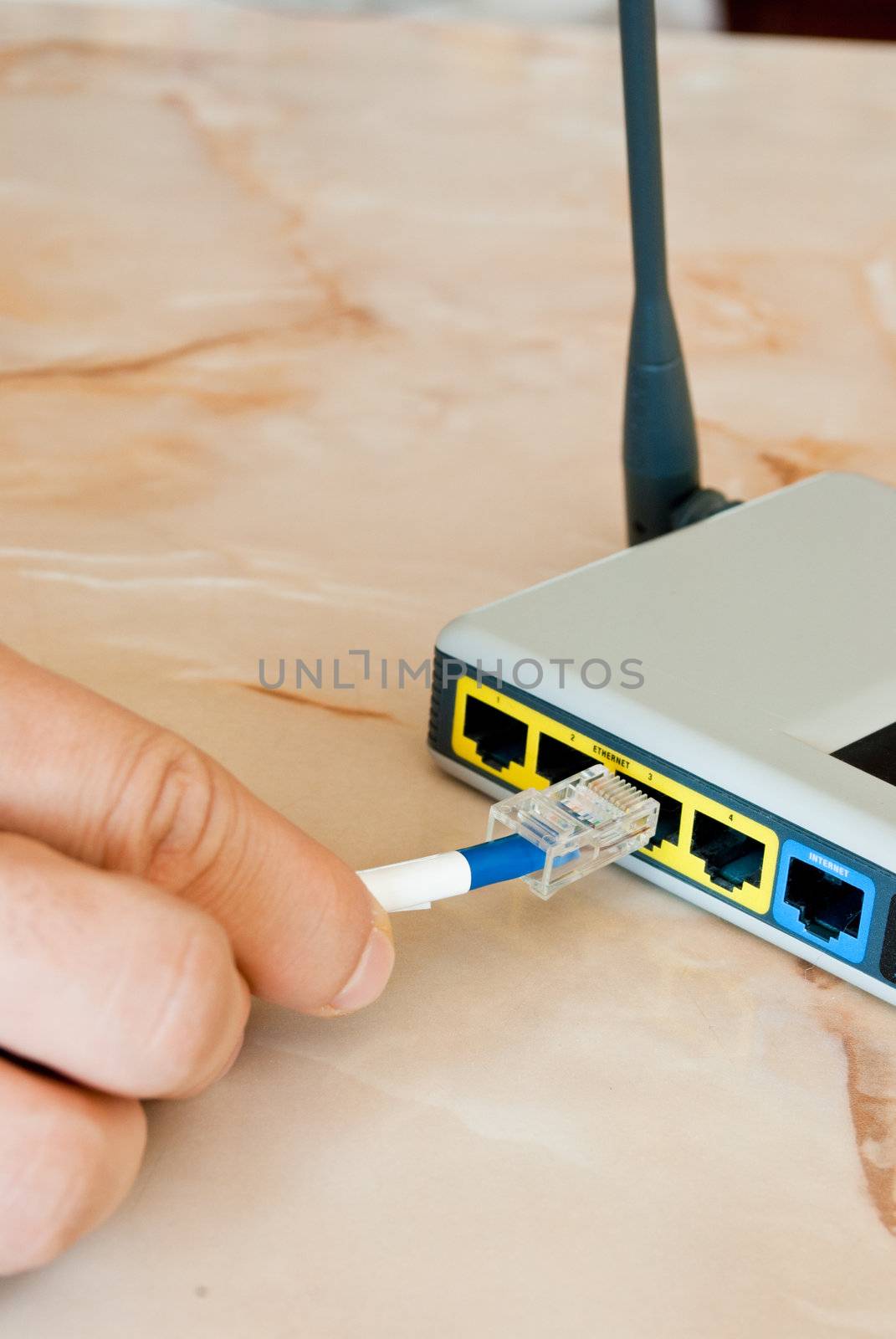 A hand pluging an ethernet cable into ab old a router