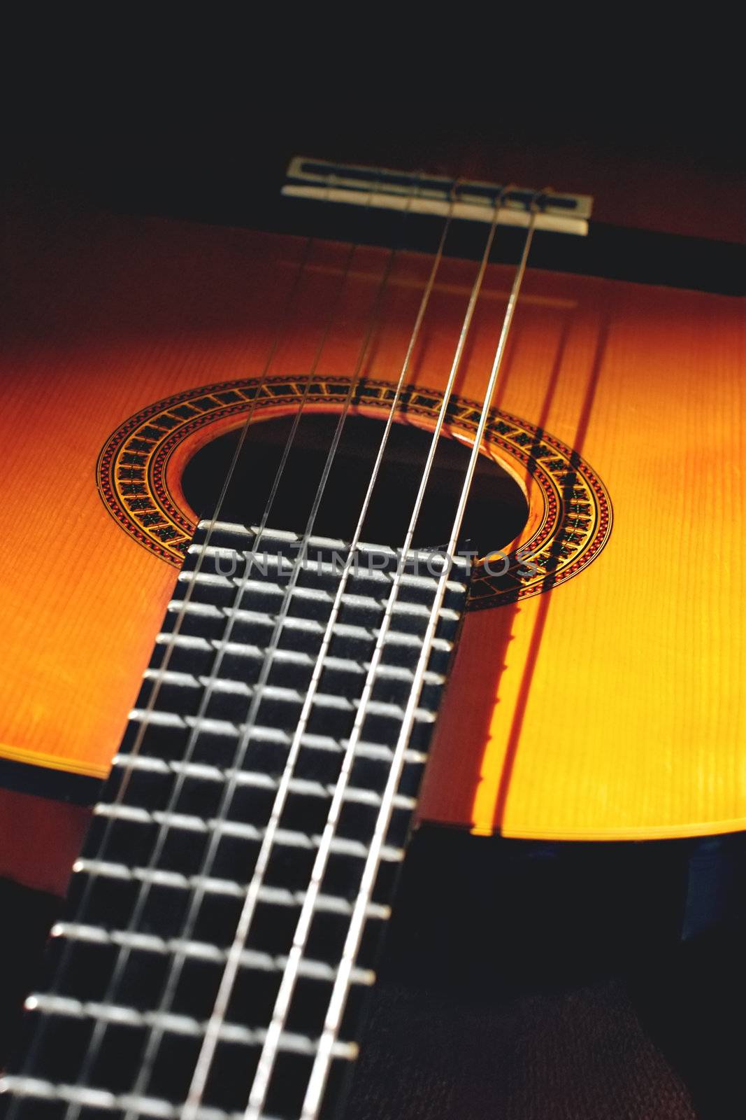 close up of spanish style acoustic guitar in shadows