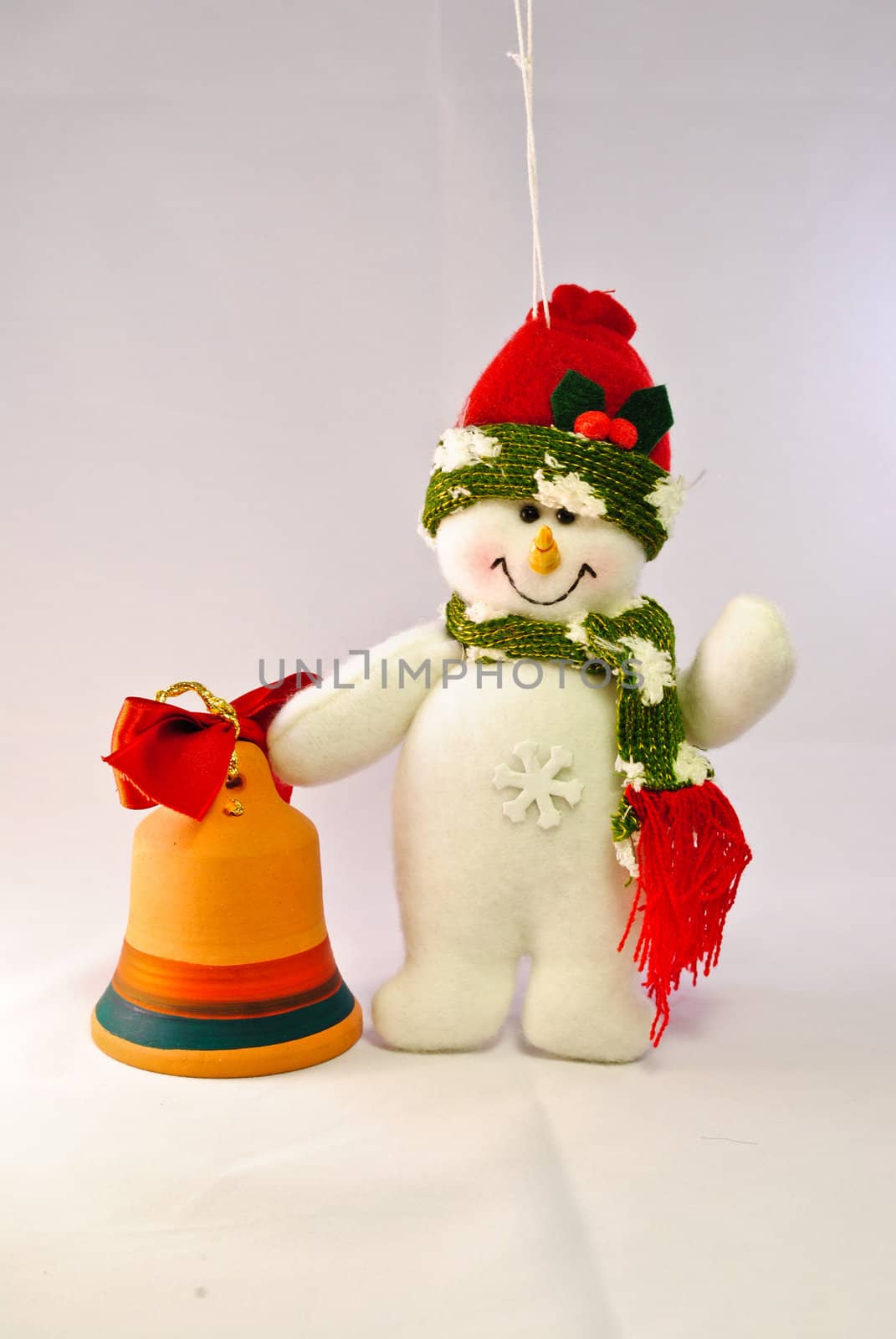 Toy snowman with orange bell and red ribbon hanged on a string