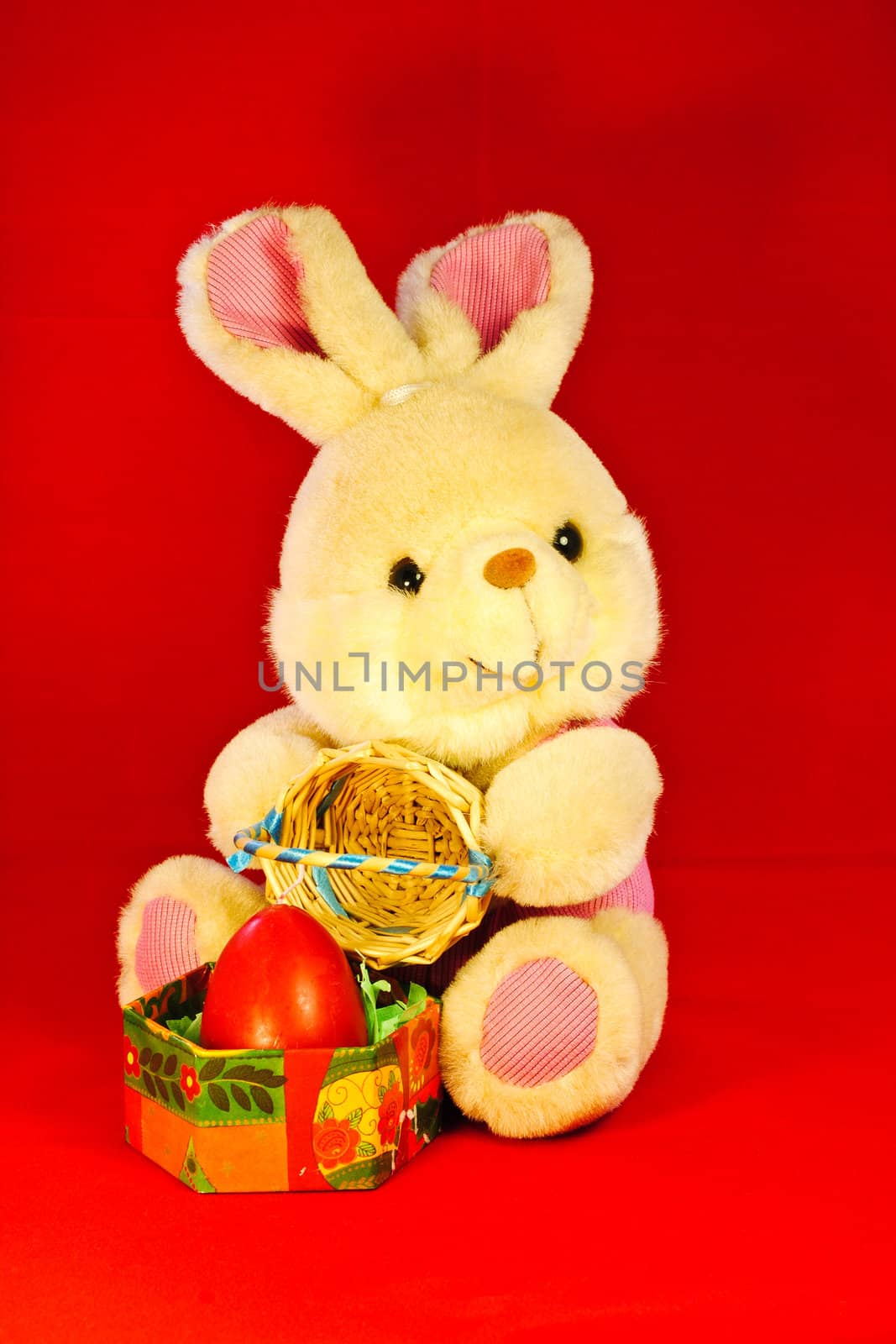 A toy bunny with a wicker basket and a red candle shaped like an egg