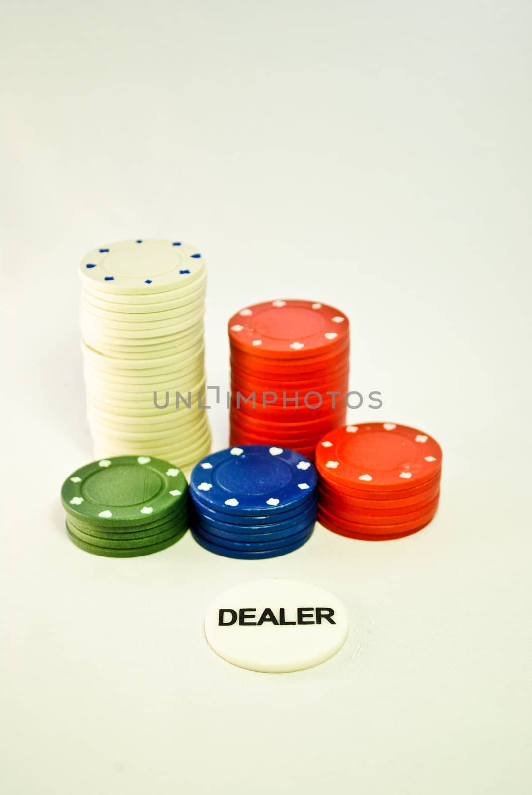 White, red, green, blue poker chips with dealer chip in front