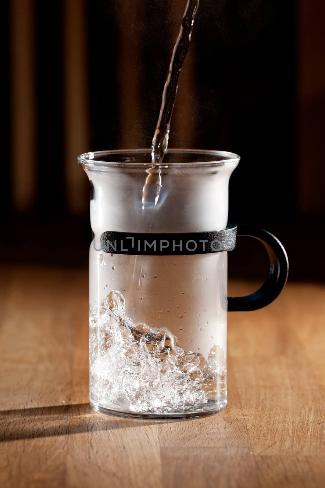 Early morning tea - glass being filled with water with strong directional light