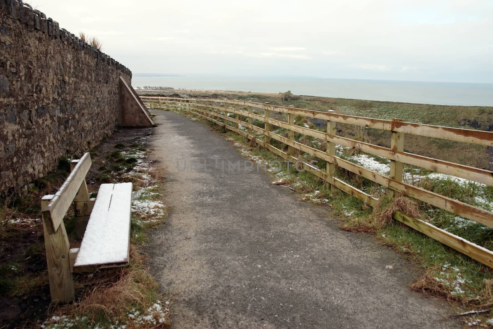 snow covered bench on the ballybunion cliffside walk in winter
