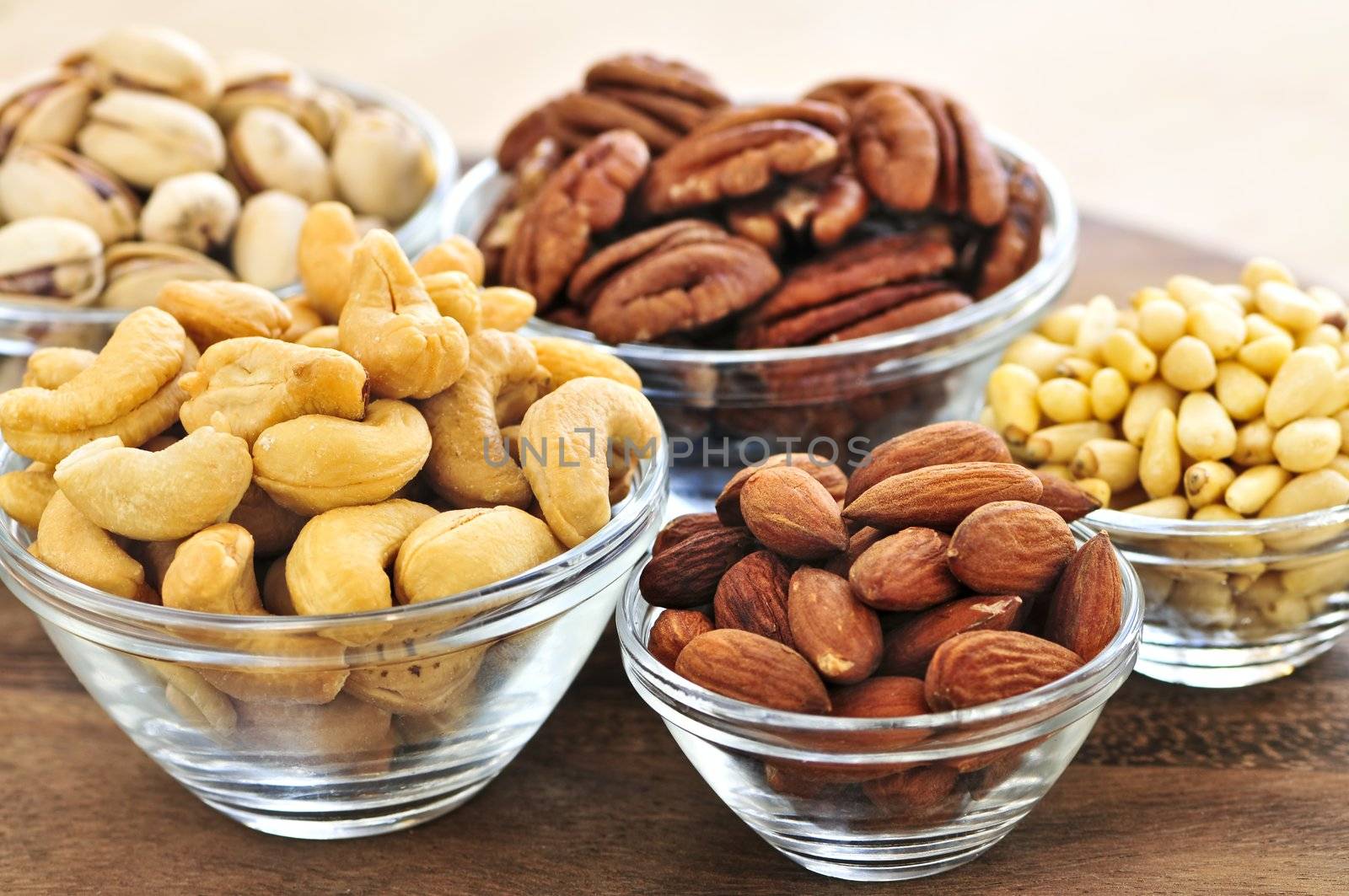 Almonds, cashews pistachio and pine nuts in glass bowls