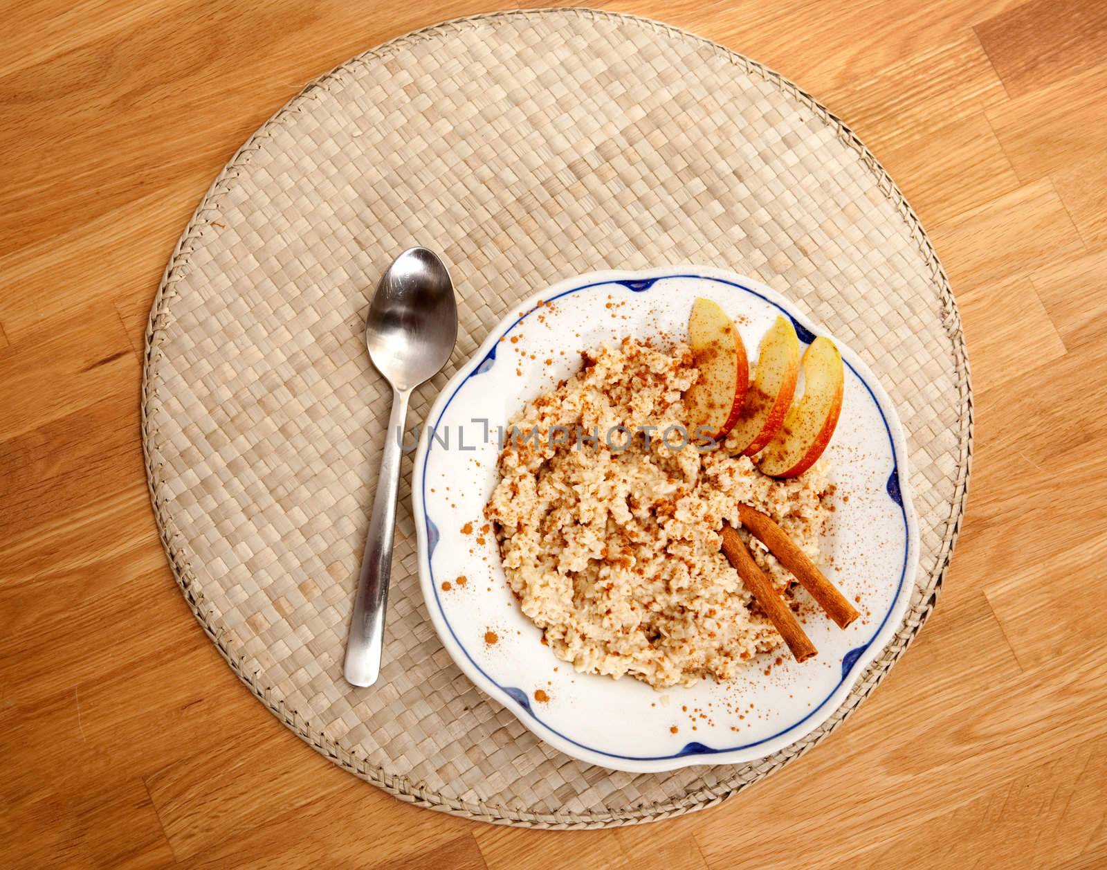 A bowl of porridge with apple and cinnamon spices viewed from above