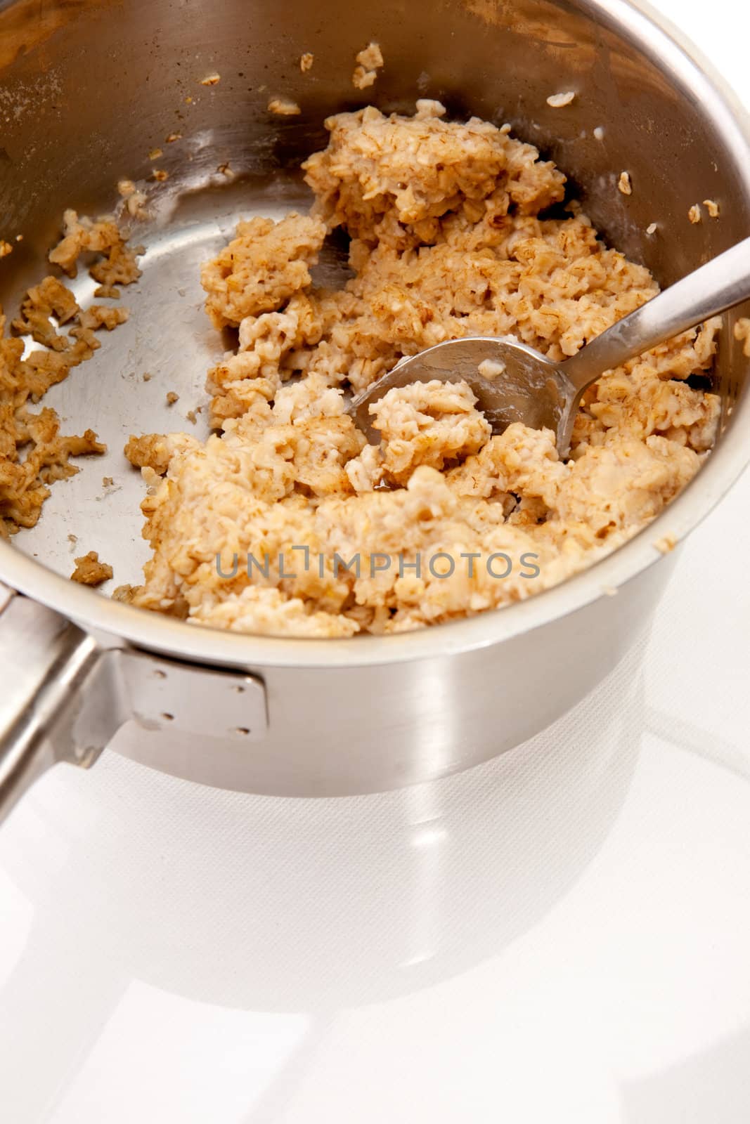 A pot of old cold porridge on a reflective white background