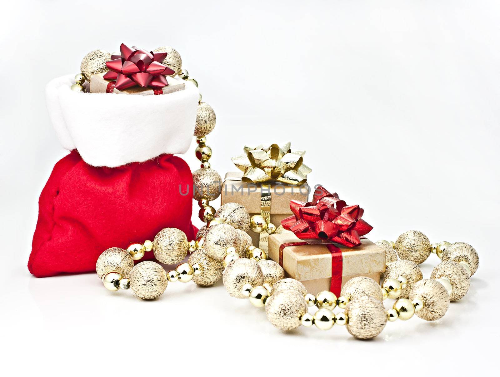 On a white background Christmas gift bag with gifts and golden ball strings.
