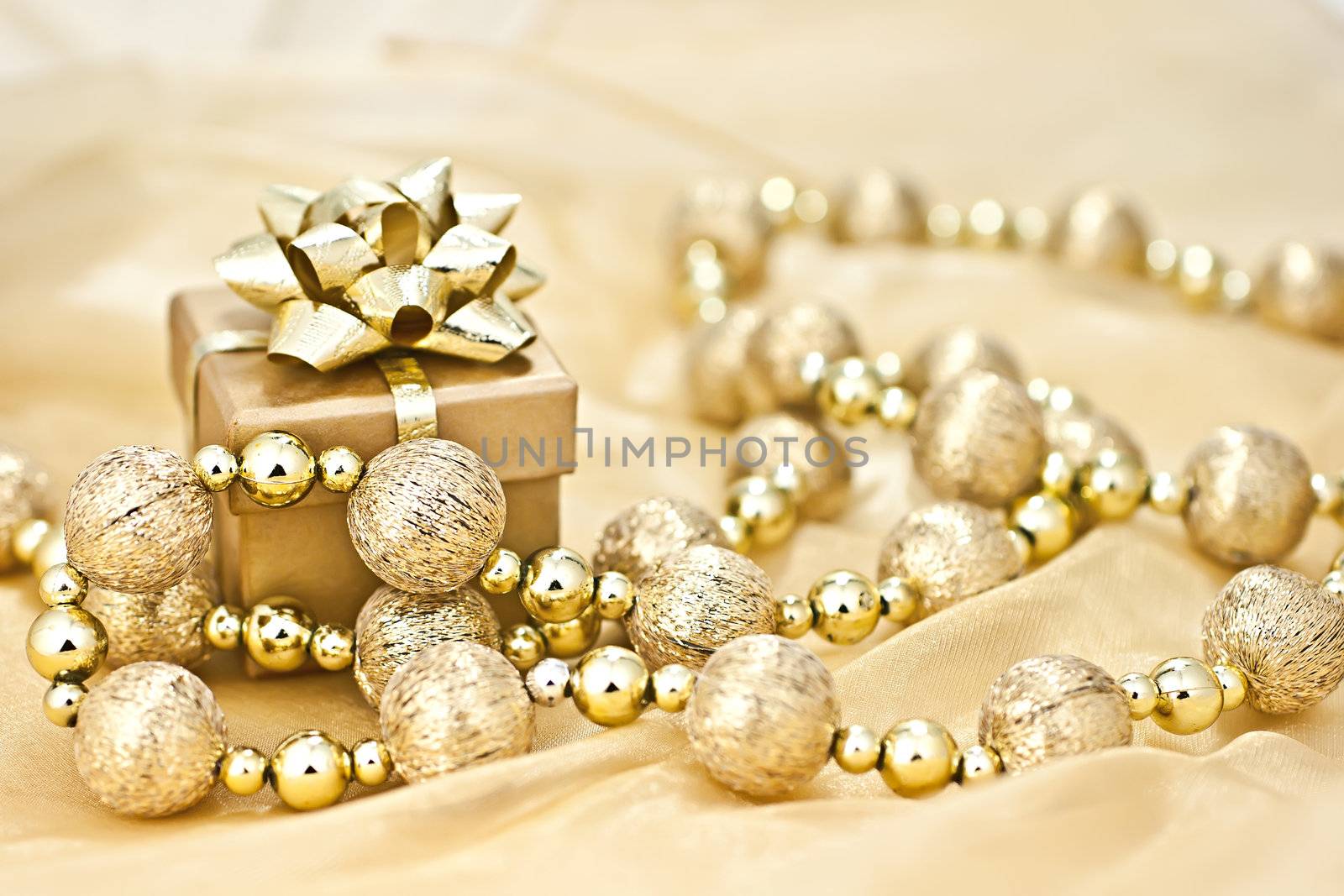 The gold background gold gift box with a string of Christmas ornamental ball.
