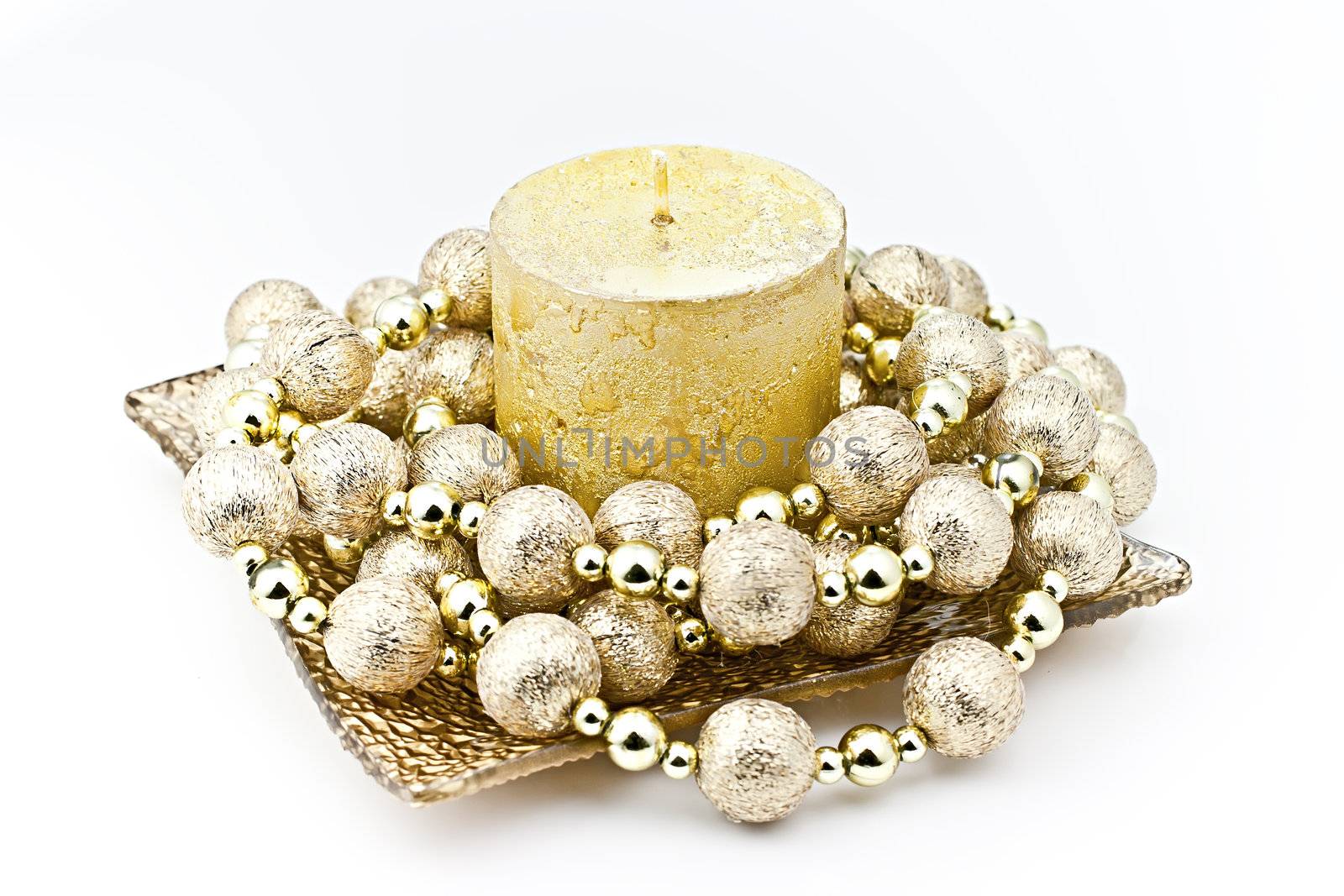 Isolated on white background gold candle in a glass dish with a decorative string of bombs.

