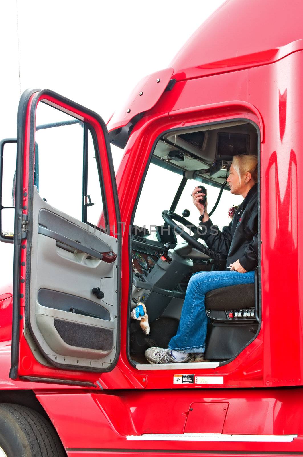 Pretty blonde woman in a big rig talking on her CB radio to other truck drivers.