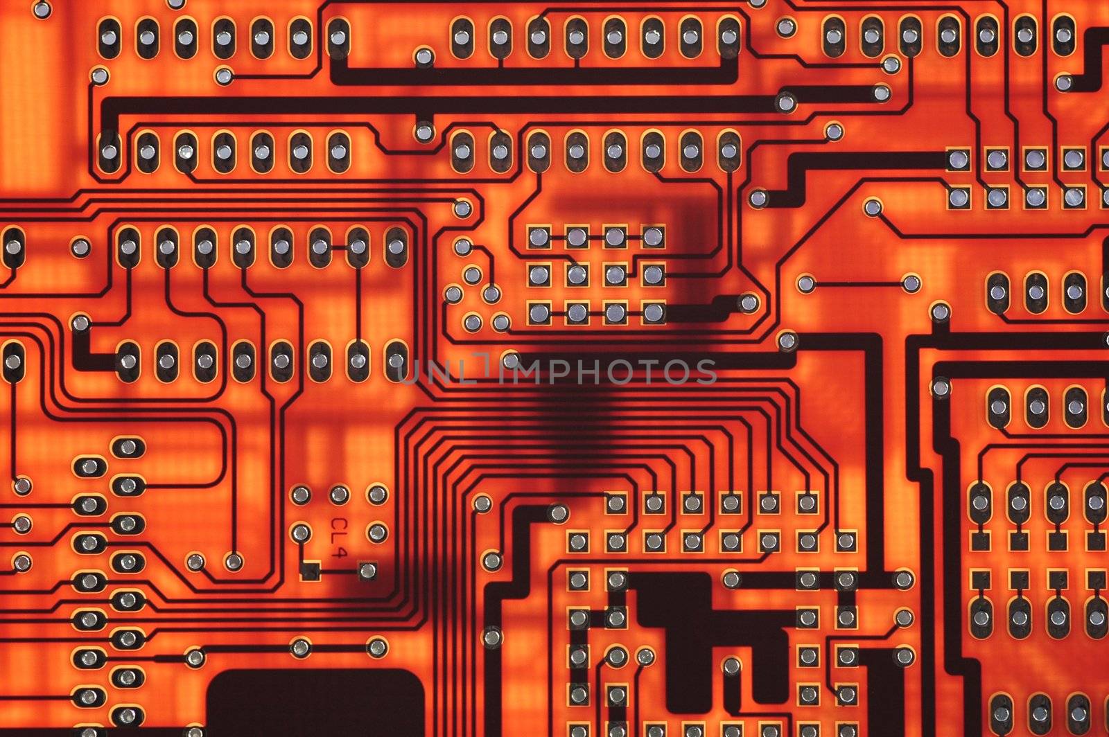 close-up of red computer circuitboard solder tracks and holes