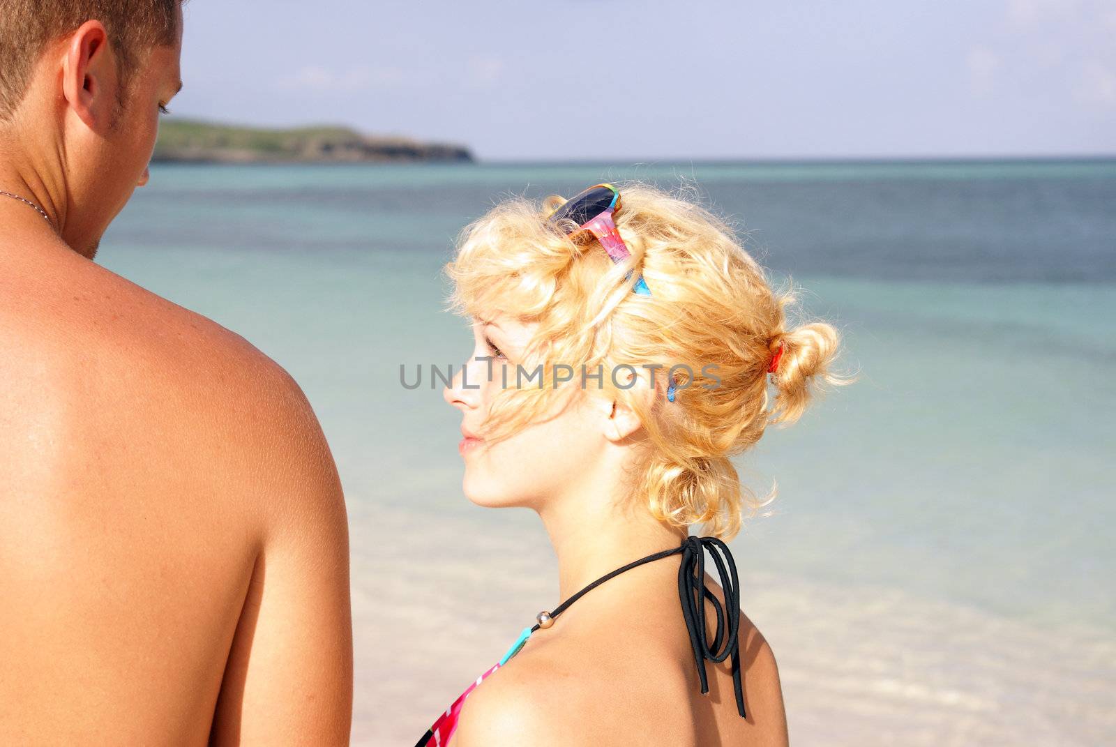 A young couple starring into each others eyes at the beach.