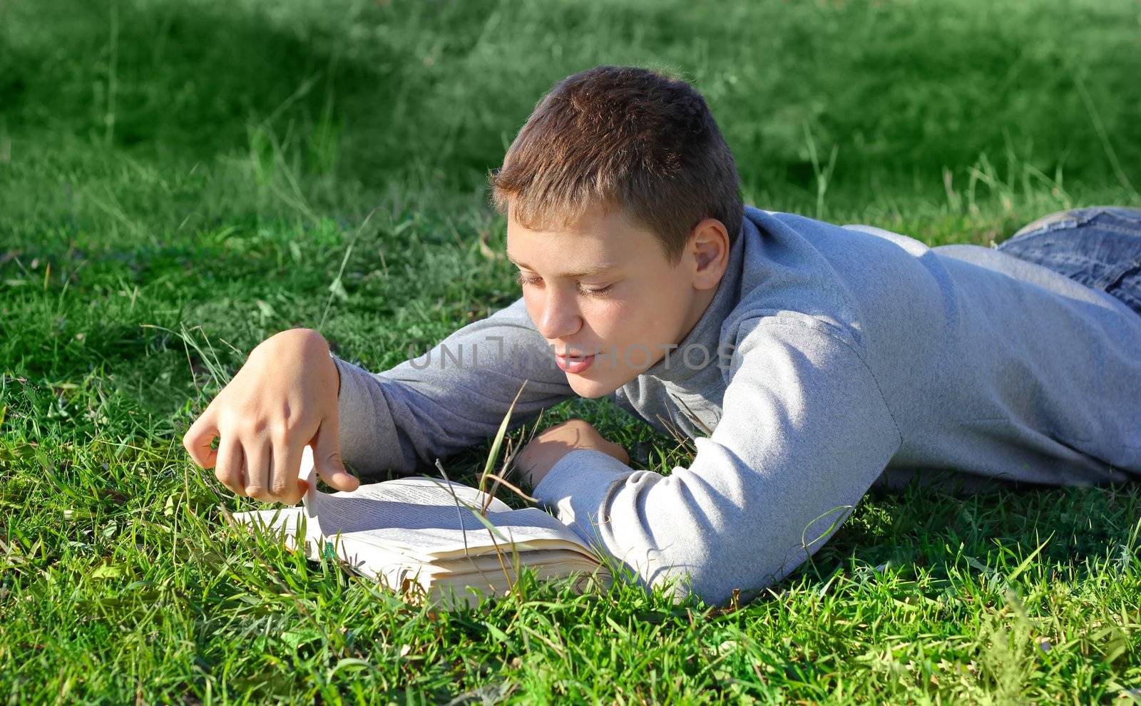 boy with a book on green grass