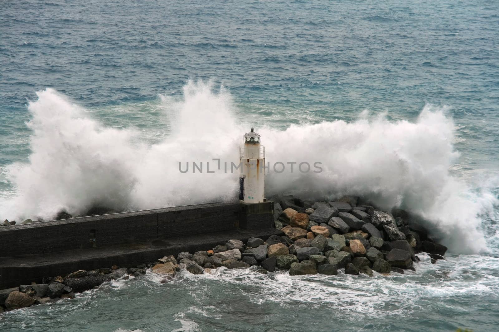 waves break on the lighthouse at Camogli, Italy