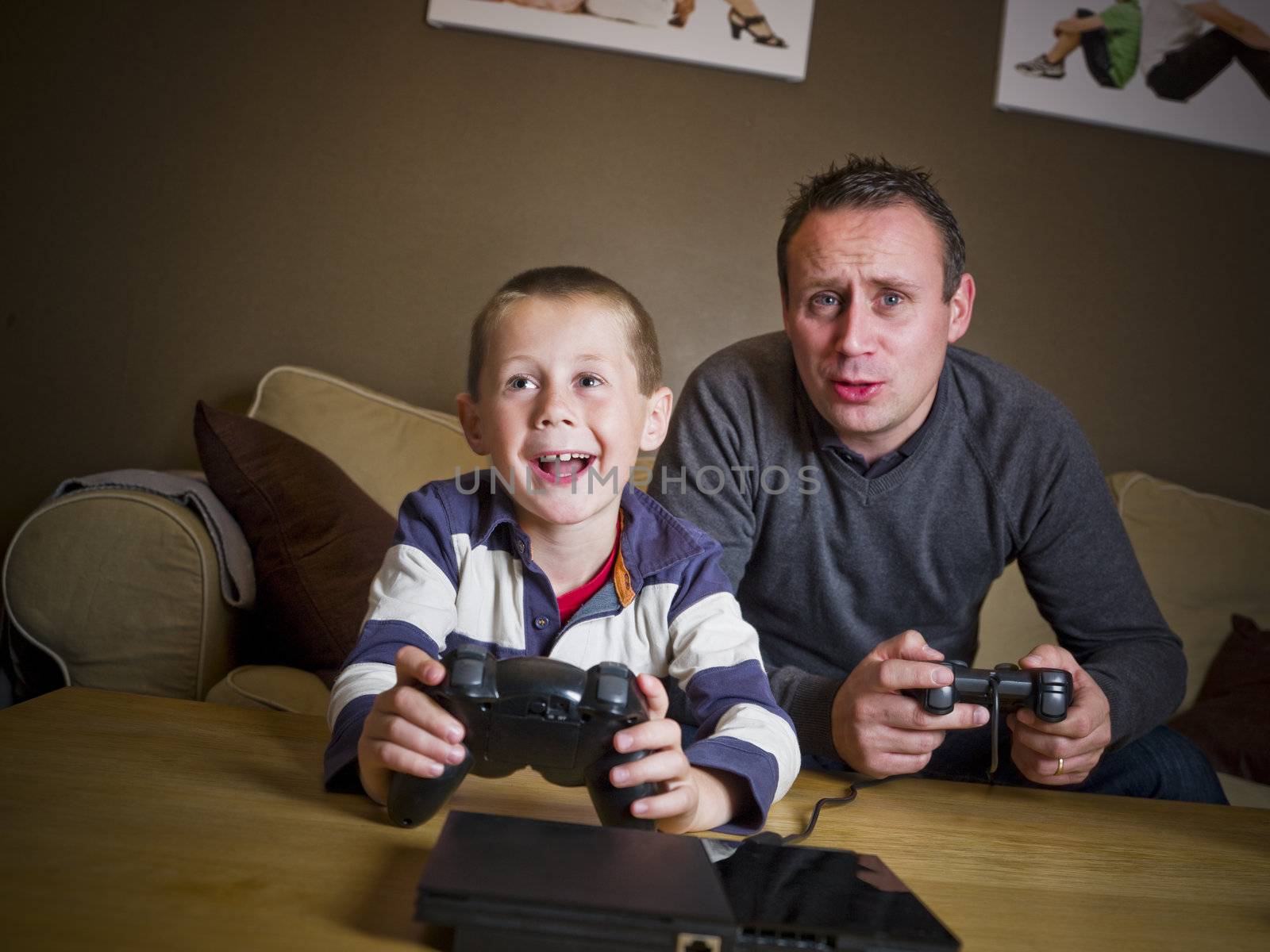 Father and son playing Video Games sitting in the Sofa