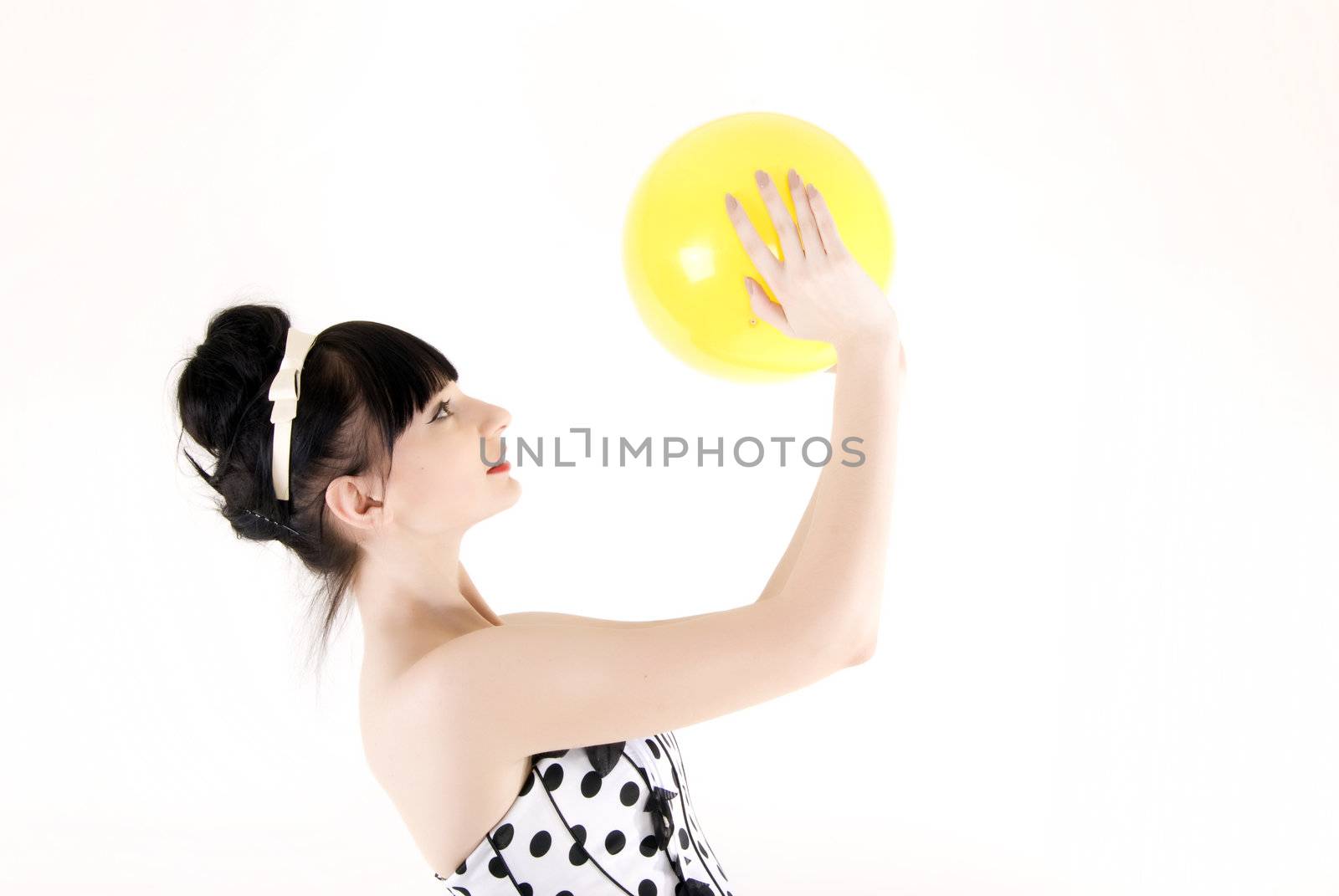 Portrait of a young beautiful brunette posing with yellow ball