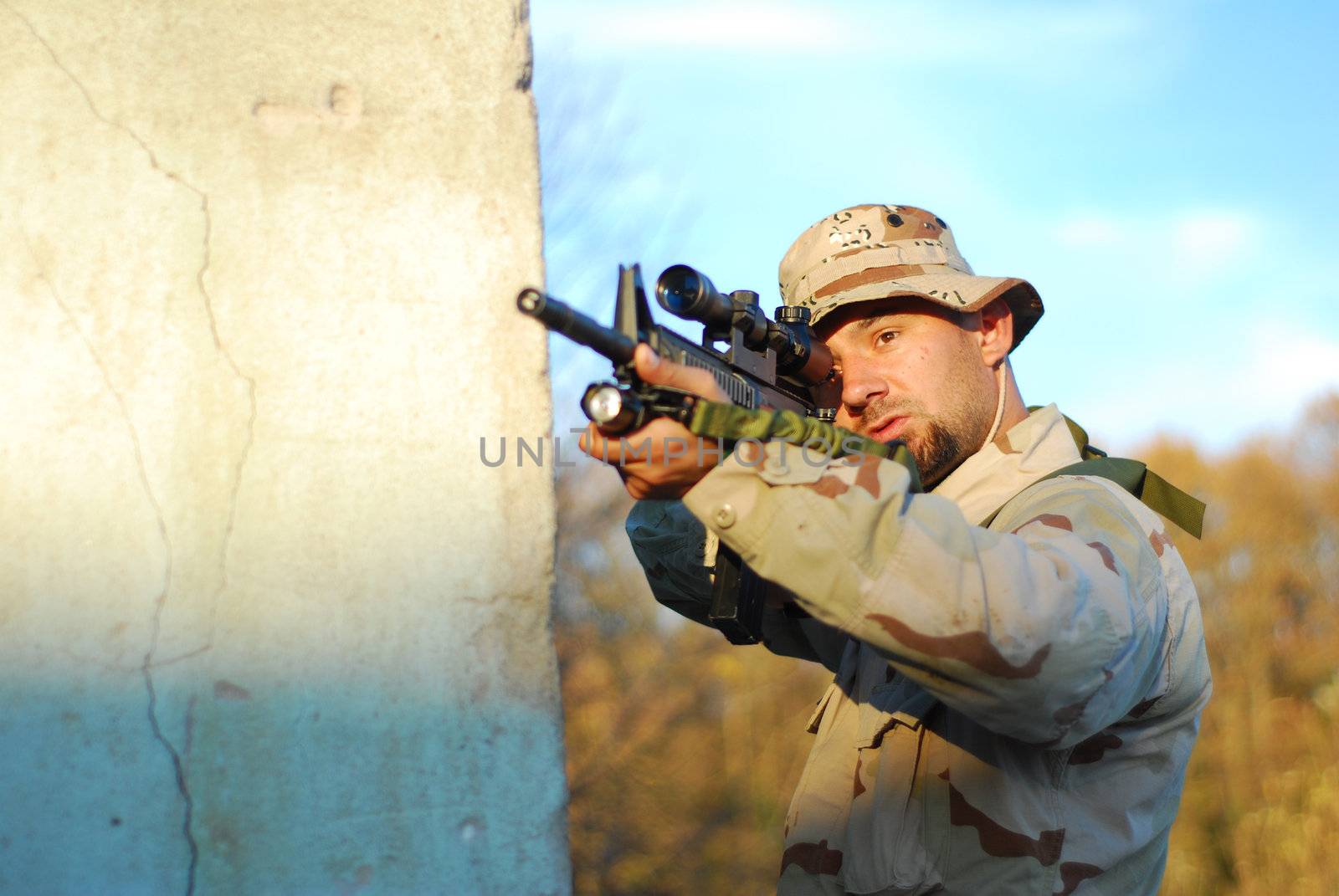 Soldier in camouflage aiming with his rifle outdoor