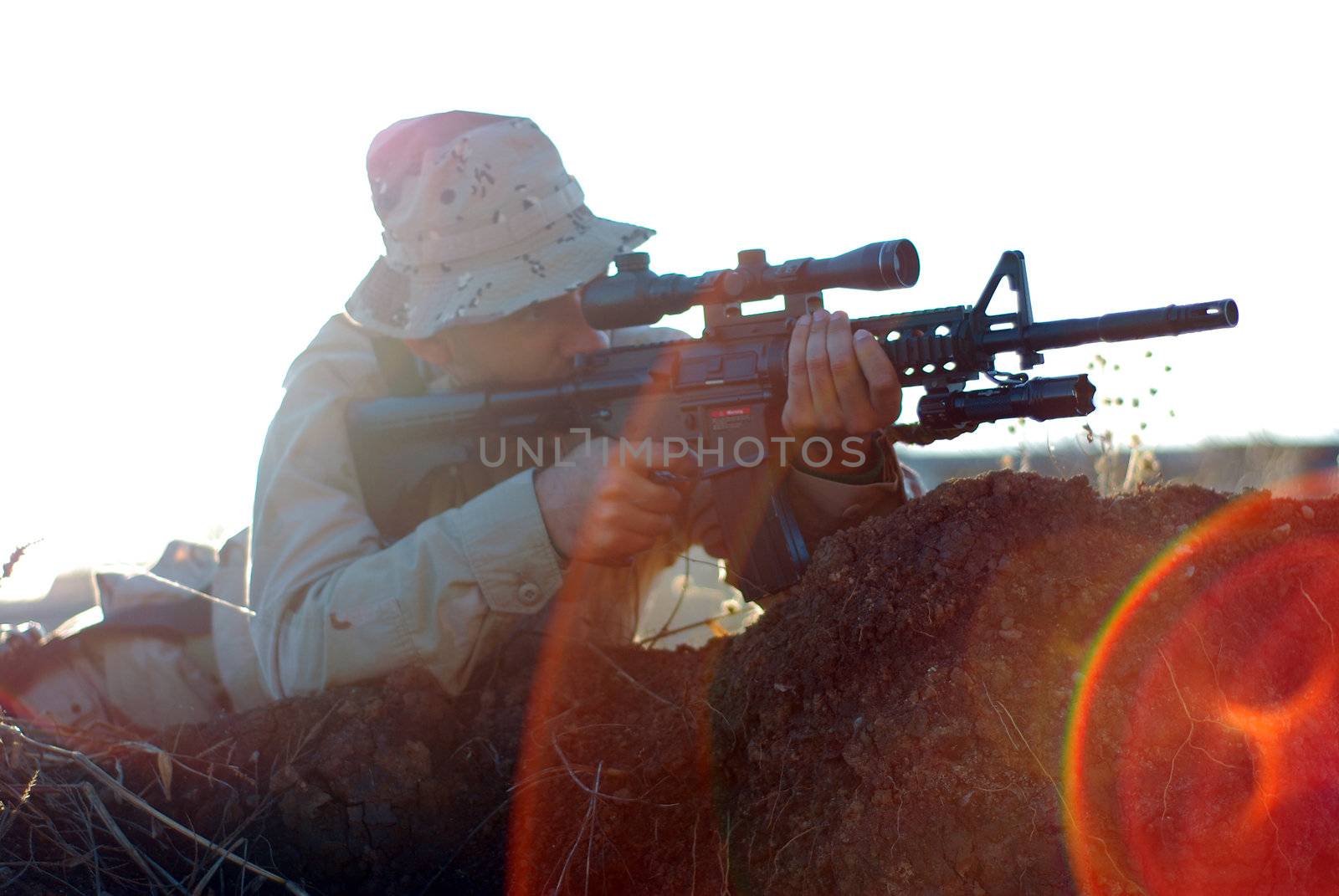 Soldier in camouflage aiming with his rifle outdoor with lens flare effect