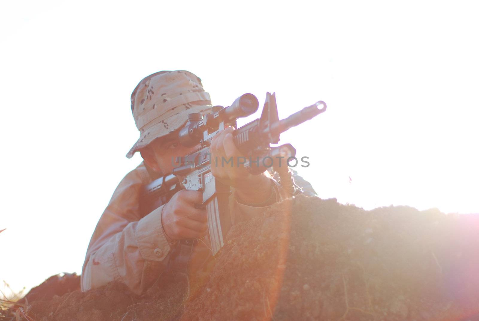 Soldier in camouflage aiming with his rifle outdoor with lens flare effect