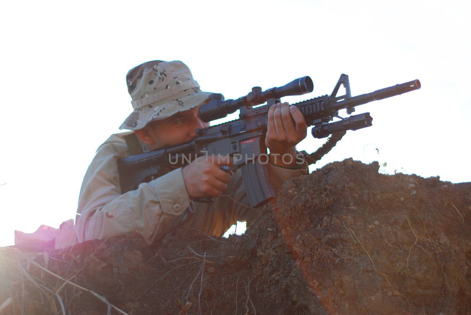 Soldier in camouflage aiming with his rifle outdoor with lens flare effect