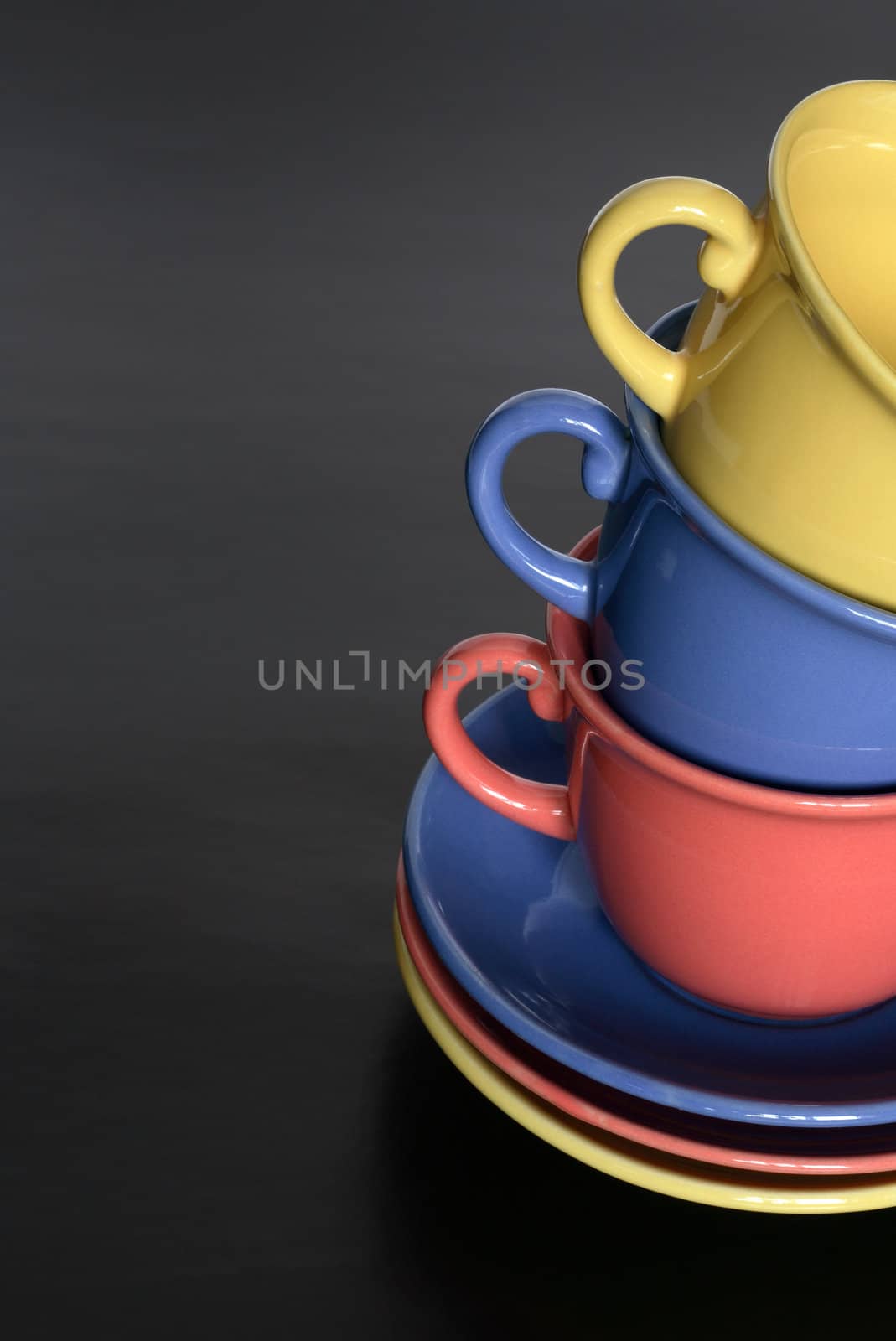 Stack of three motley cups standing on black background with copy space