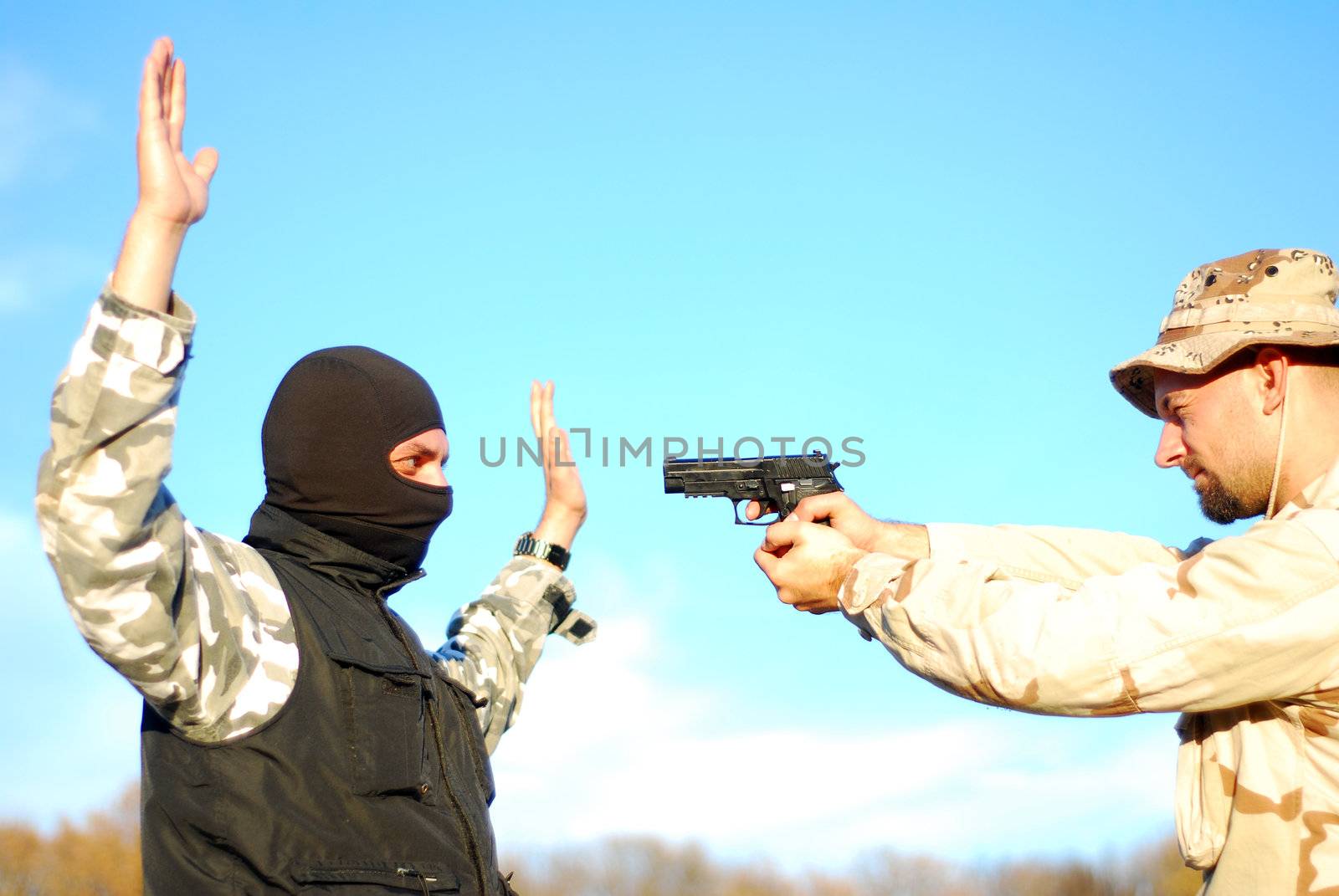 US soldier taking armed criminal under arrest with blue sky behind