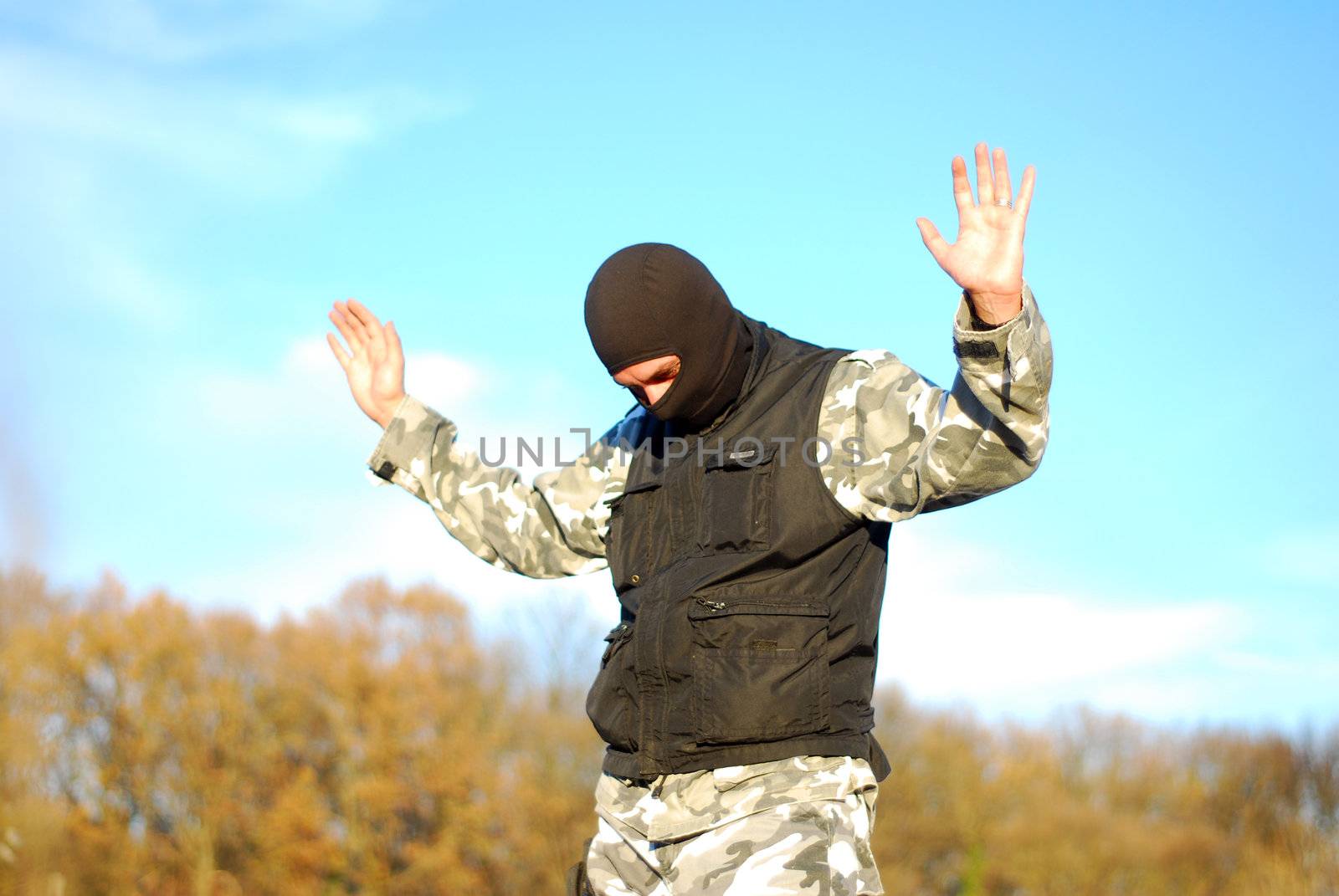 The surrendered criminal in a black mask  with blue sky behind