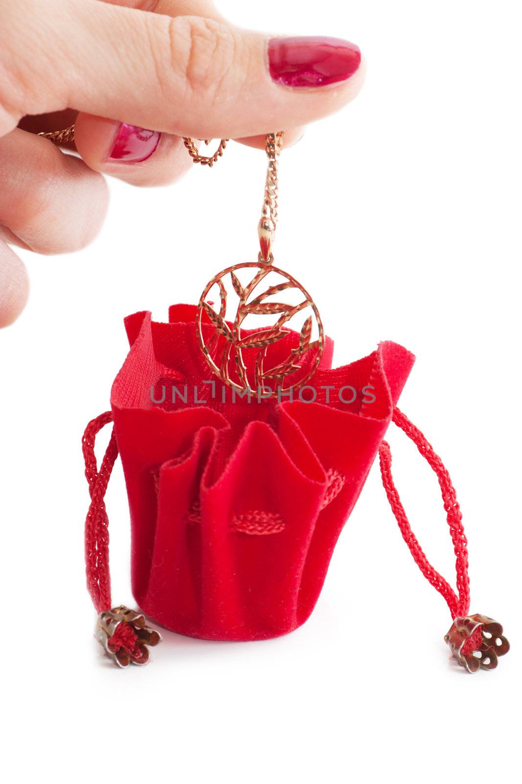 A female hand put golden chain into little red bag isolated over white