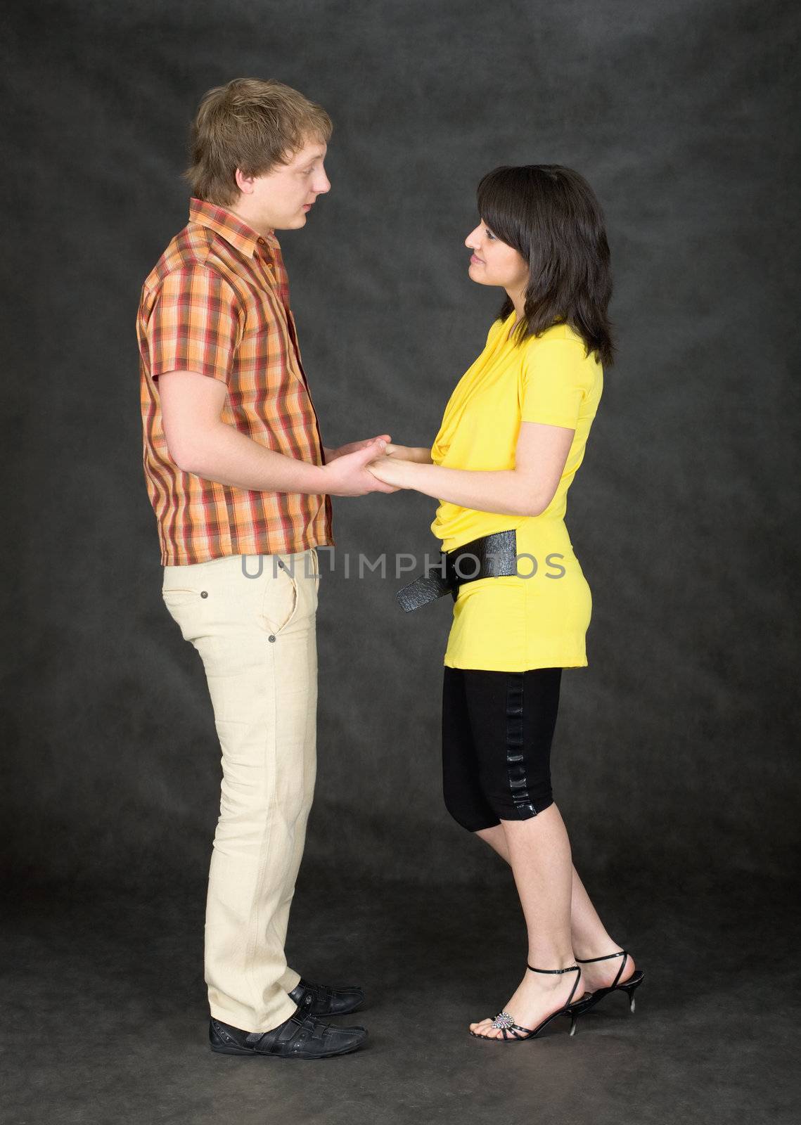 Young pair keeps for hands on a black background