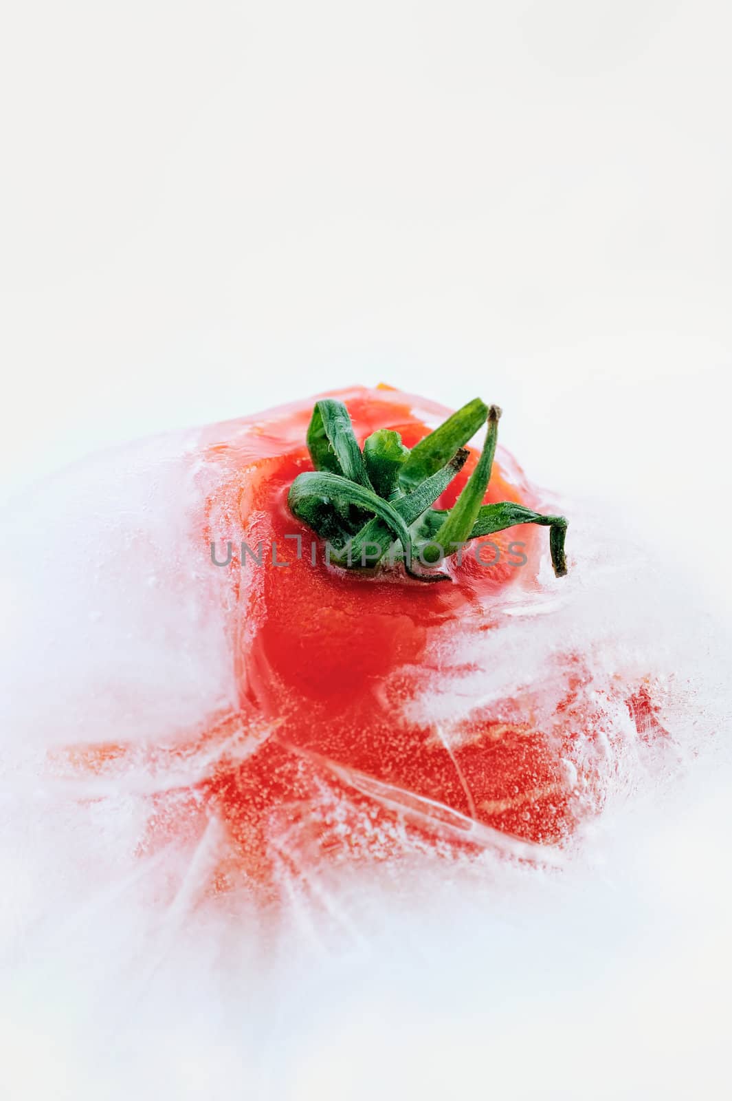 Tomato frozen in ice cube, isolated on white background