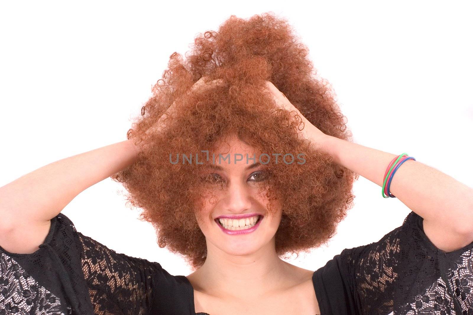 Beautiful young teenager with red afro wig and a big smile grabbing her hair