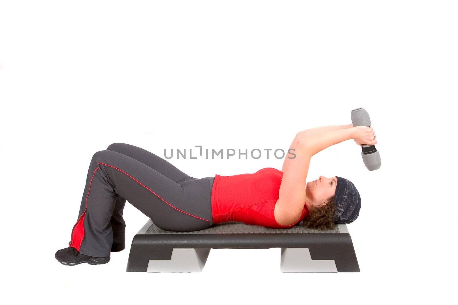 Pretty woman doing triceps curls while lying on a step