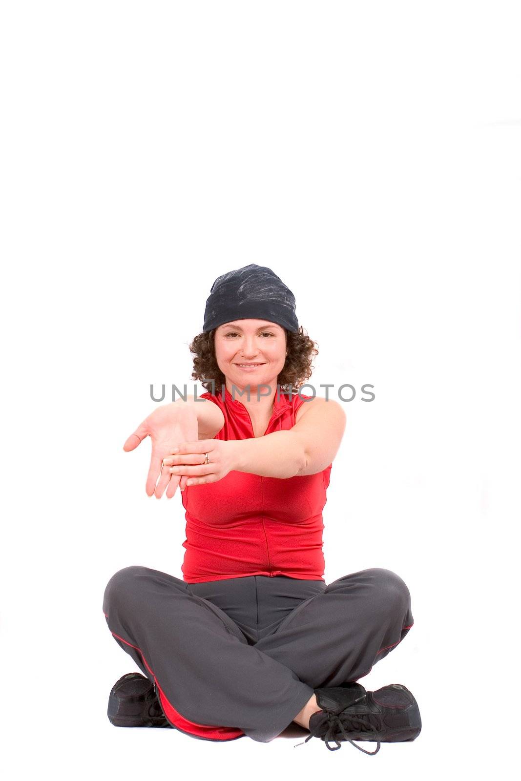 Pretty woman doing an arm stretch while sitting crosslegged on the floor