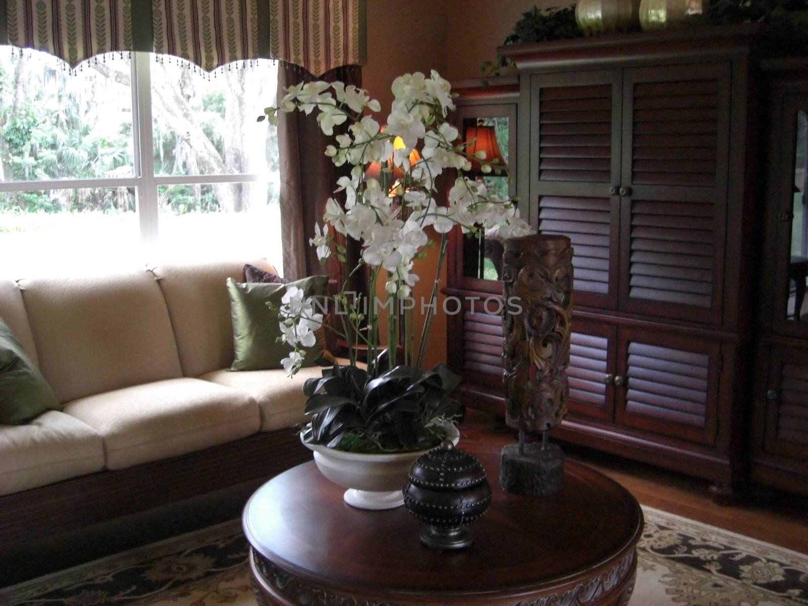 A room with elegant pieces of furniture and a big center piece on a matching coffee table.