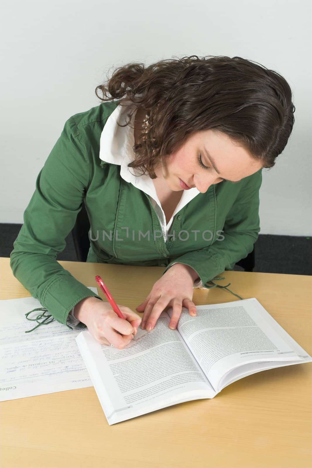 Teenager writing a little note to her friend while pretending to be learning